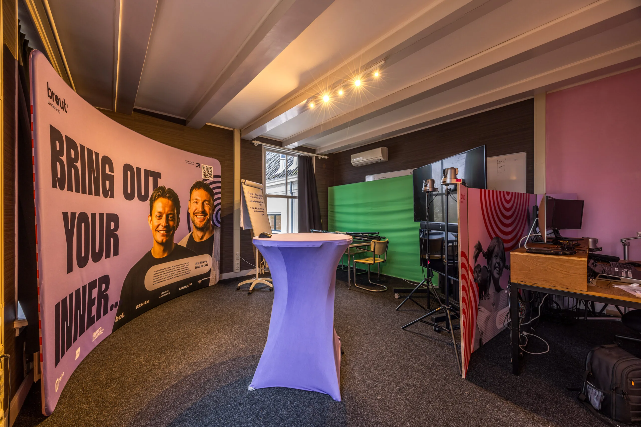 Multifunctionele studio- en werkruimte met groene schermwand, promotiemateriaal van Brout en audiovisuele apparatuur.