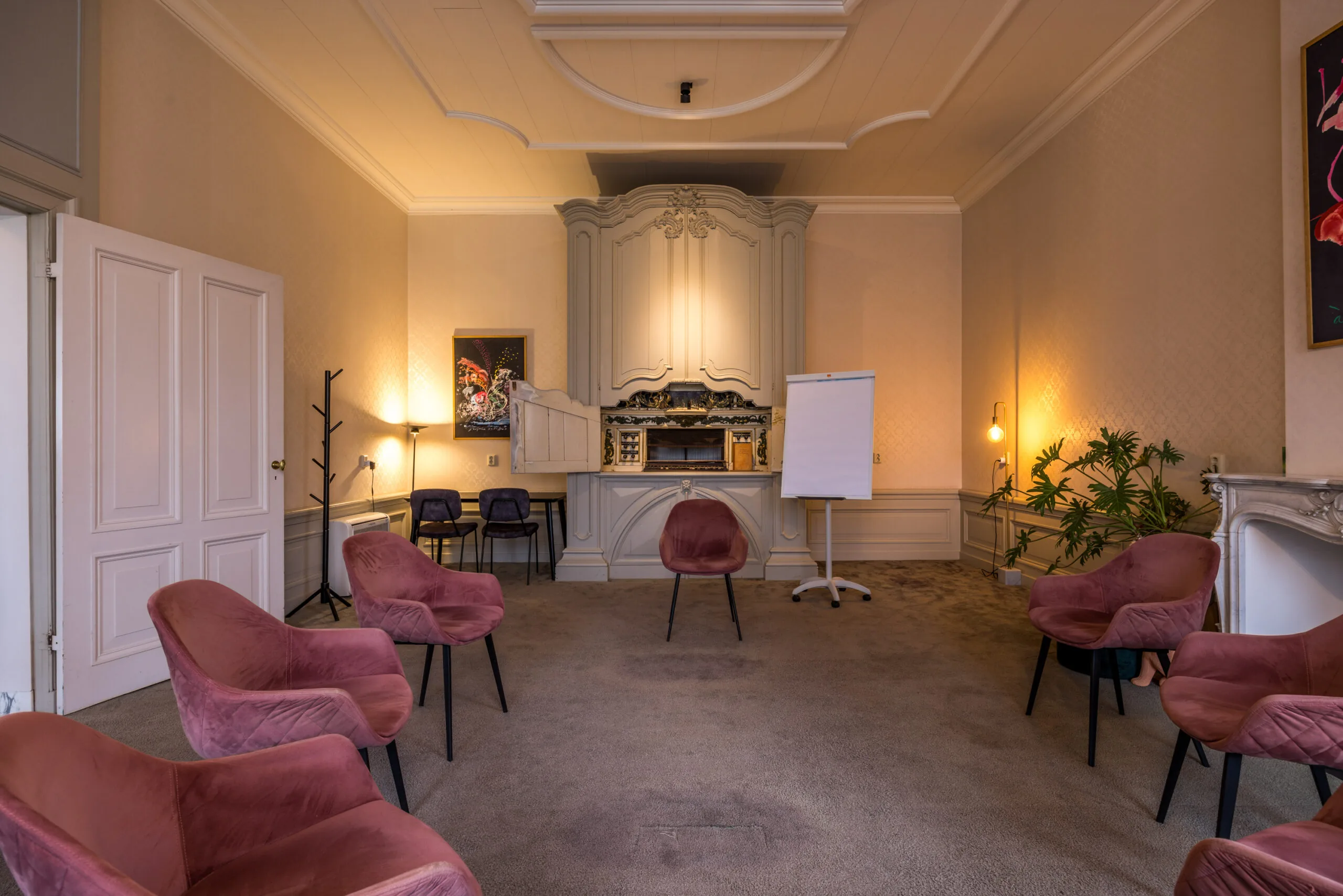 Stijlvolle vergaderruimte met roze fluwelen stoelen, een flip-over en klassieke details in een monumentaal pand aan het Zandpad.