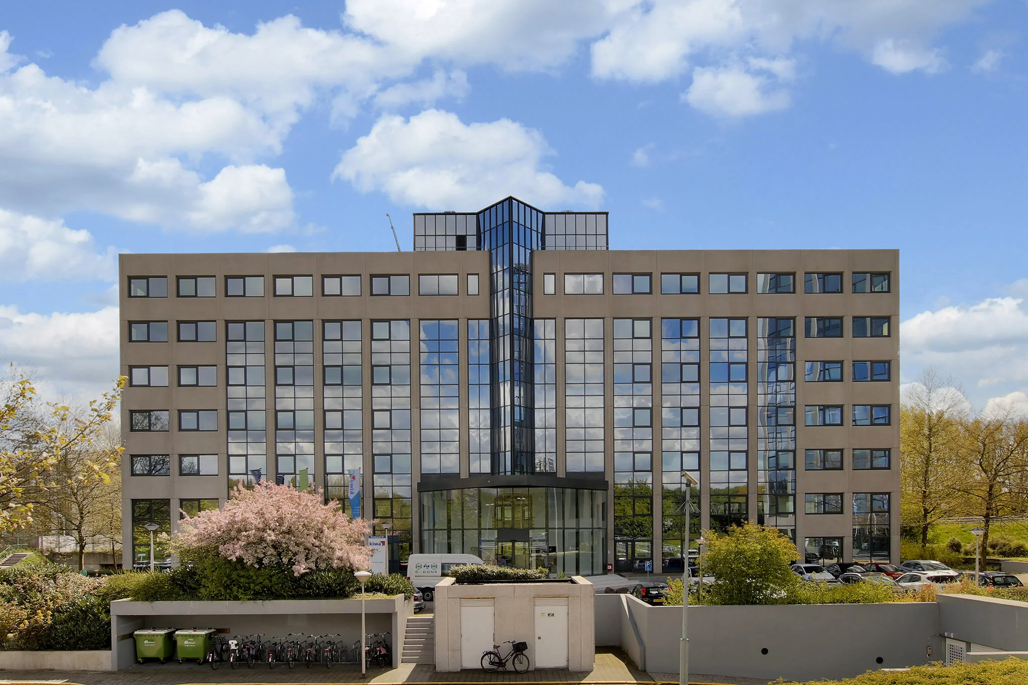 Voorgevel van een modern kantoorgebouw aan de Nevelgaarde met een glazen entree en omliggend groen.