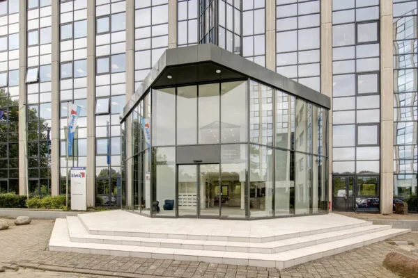 Ingang van een modern kantoorgebouw aan de Nevelgaarde met glazen gevel en bord van Kiwa Business Center.
