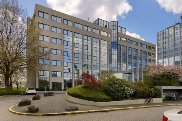 Modern kantoorgebouw aan de Nevelgaarde met spiegelende ramen en omliggende beplanting.