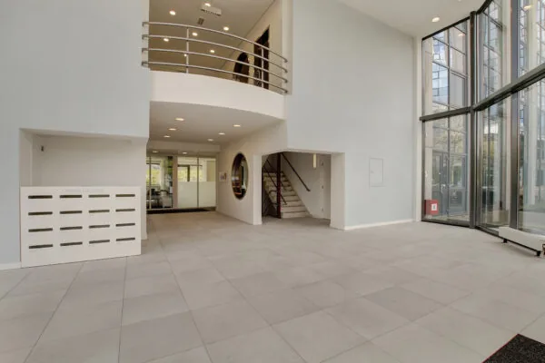 Moderne, lichte entreehal van een kantoorgebouw aan de Nevelgaarde met trappenhuis, brievenbussen en glazen gevel.