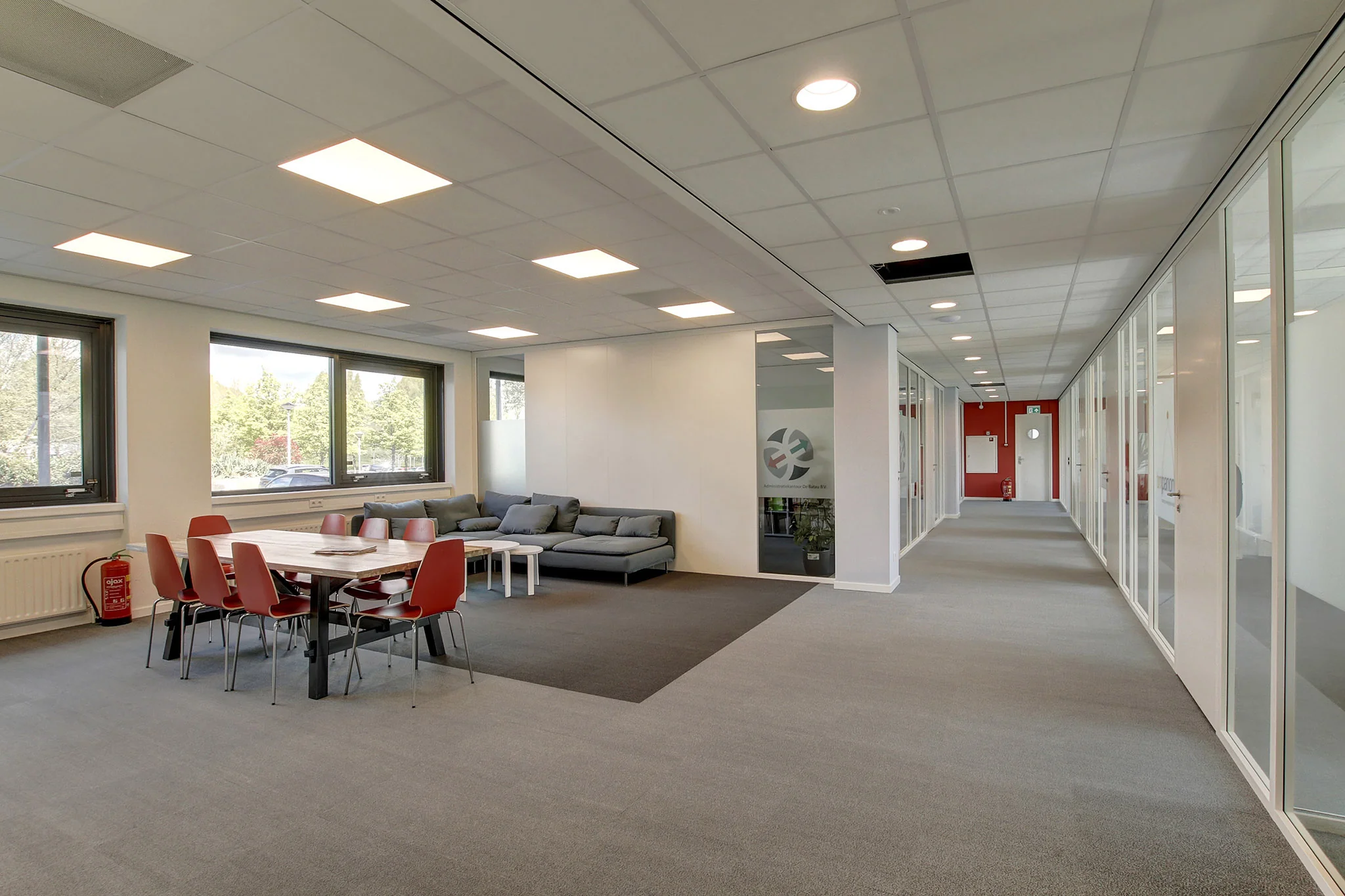 Moderne kantoorruimte aan de Nevelgaarde met vergadertafel, zithoek en glazen kantoormuren.