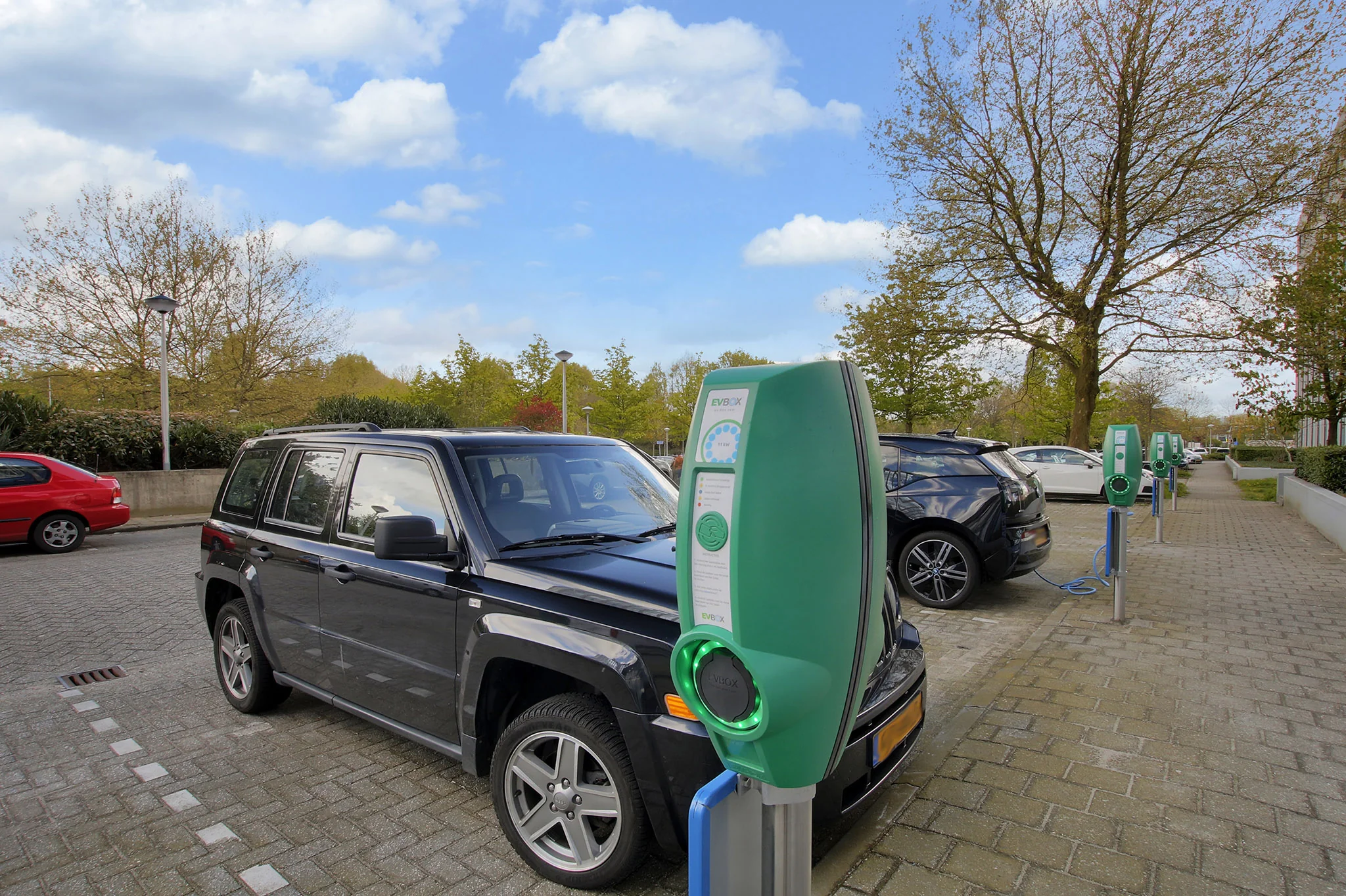 Geparkeerde auto's worden opgeladen bij een rij elektrische laadpalen aan de Nevelgaarde.