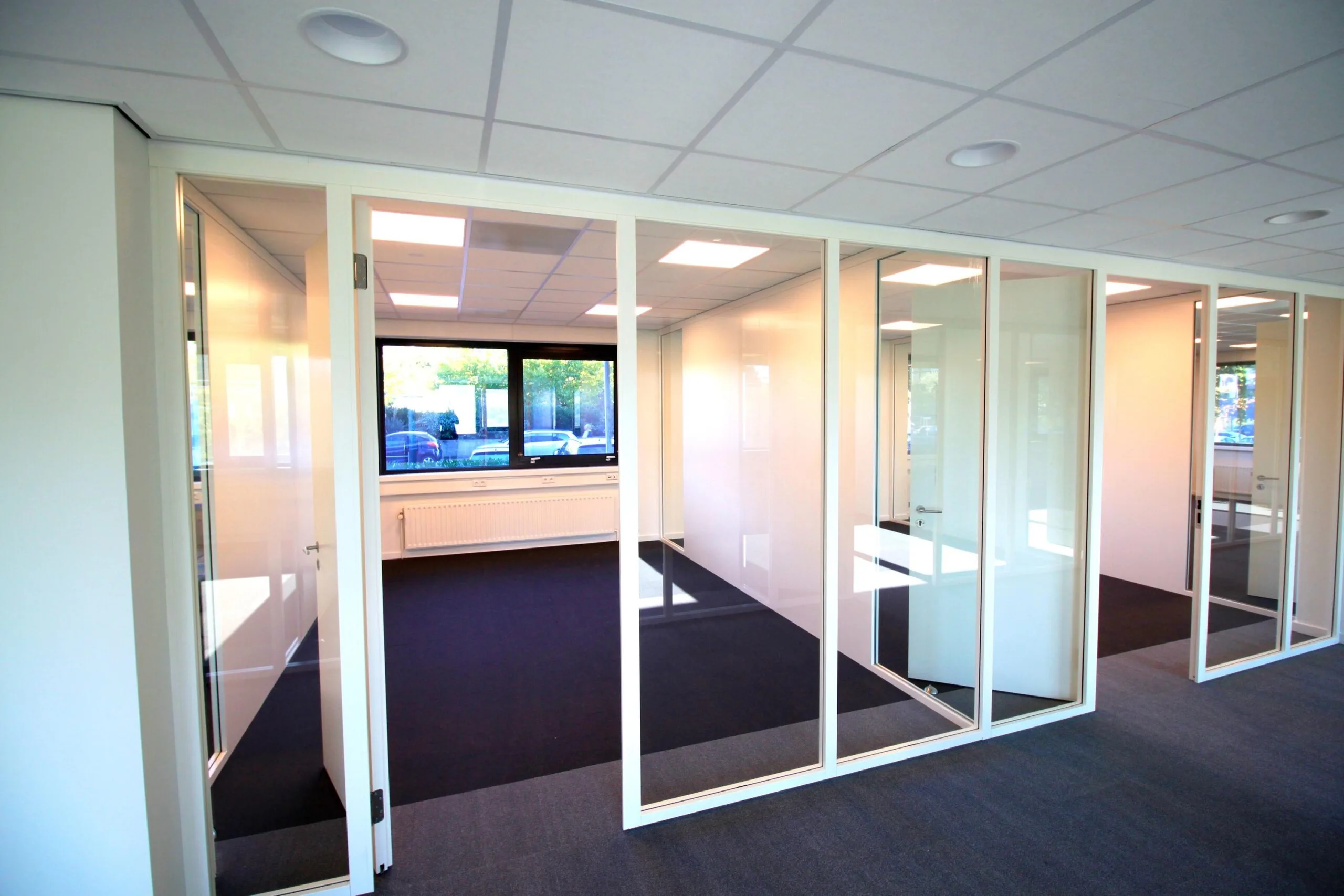 Moderne kantoorruimte aan de Nevelgaarde met glazen scheidingswanden en grote ramen.