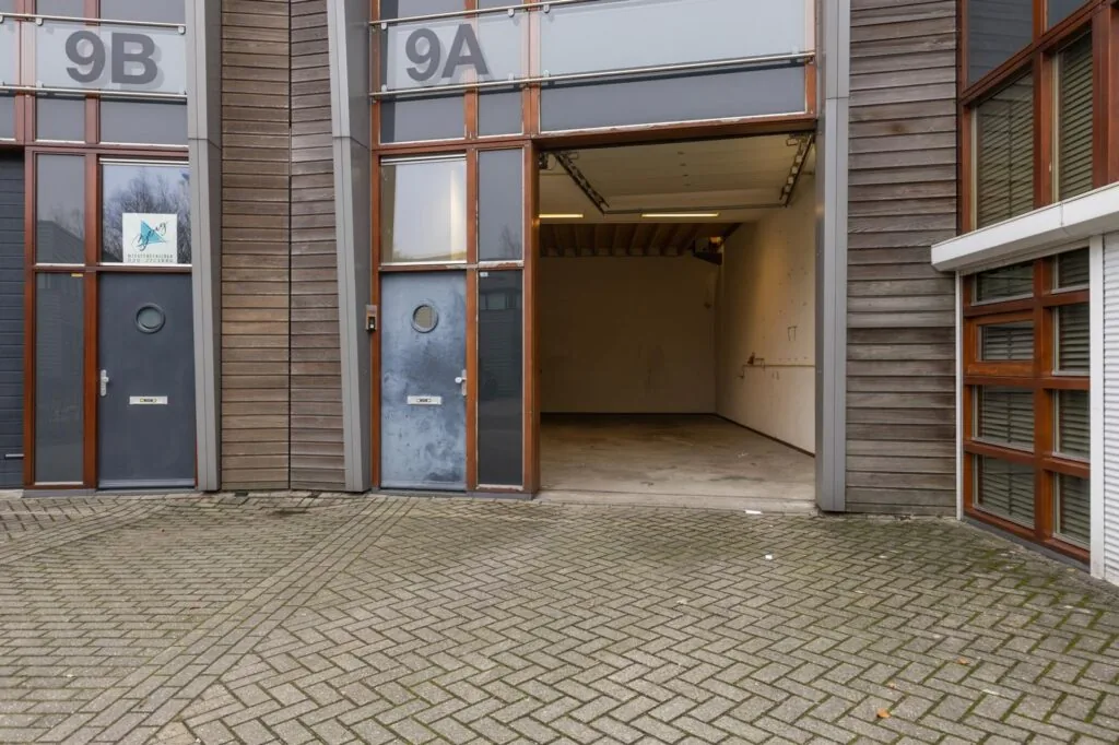 Vooraanzicht van een lege bedrijfsunit met open garagedeur aan de Tennesseedreef, genummerd 9A.