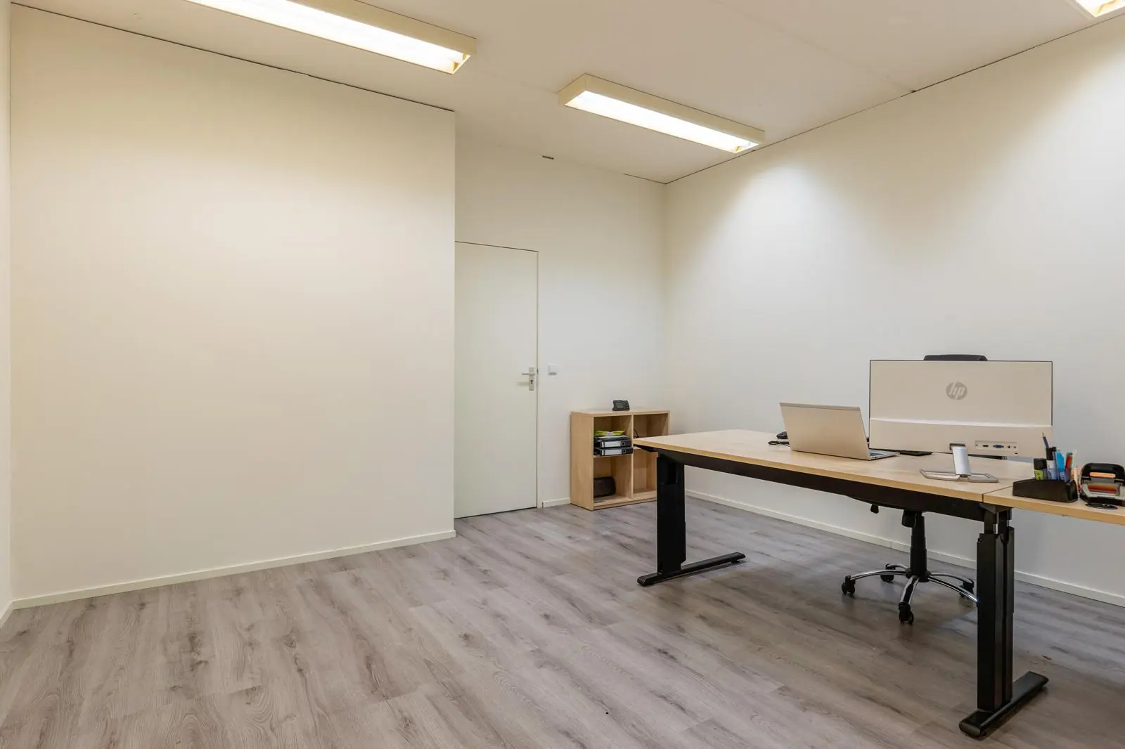 Modern en minimalistisch ingericht kantoor aan de Tennesseedreef met houten vloer, bureau en computeropstelling.