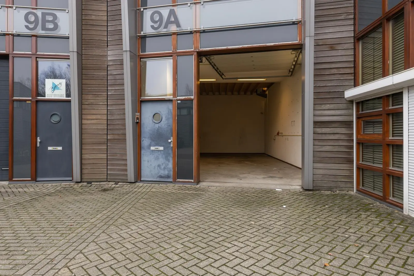 Voorgevel van bedrijfsunit 9A aan de Tennesseedreef met open garagedeur en gesloten toegangsdeur.