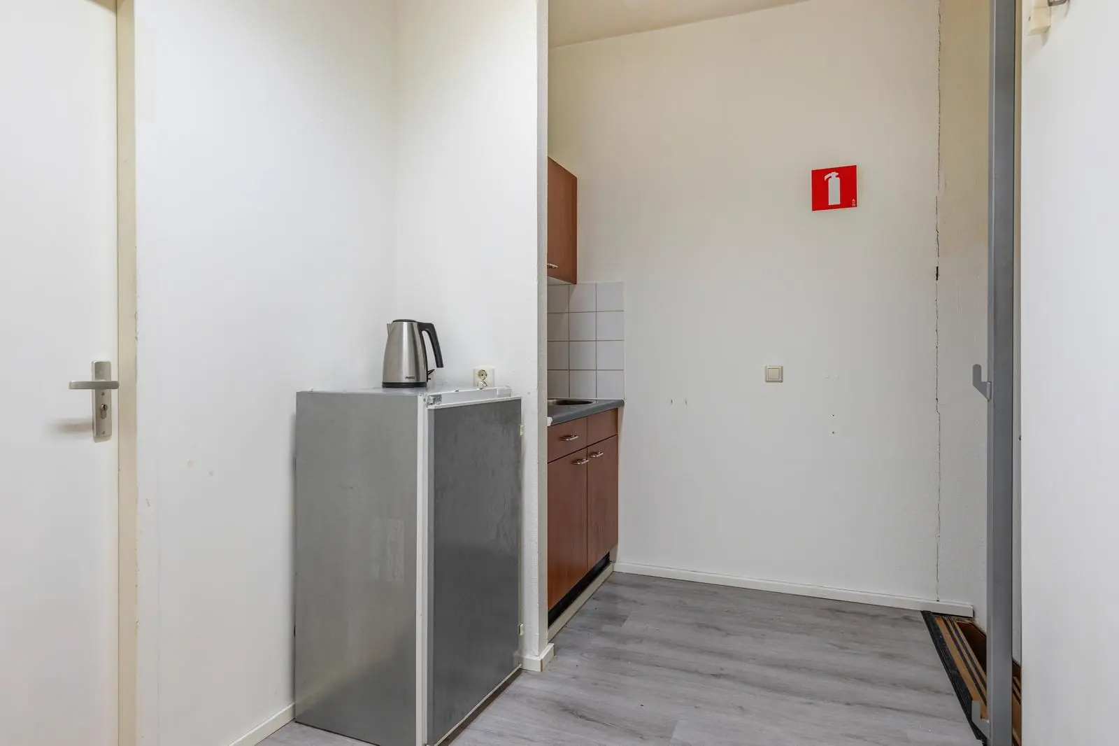 Kleine kitchenette aan de Tennesseedreef met koelkast, waterkoker en keukenkastjes.