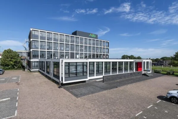 Modern kantoorgebouw aan de Lindtsedijk met het logo van Jiffy op het dak en een parkeerterrein op de voorgrond.