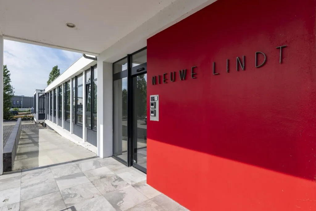 Ingang van het gebouw "Nieuwe Lindt" met een rode gevel en moderne glazen entree.