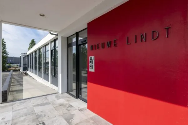Ingang van het gebouw "Nieuwe Lindt" met een rode gevel en moderne glazen entree.