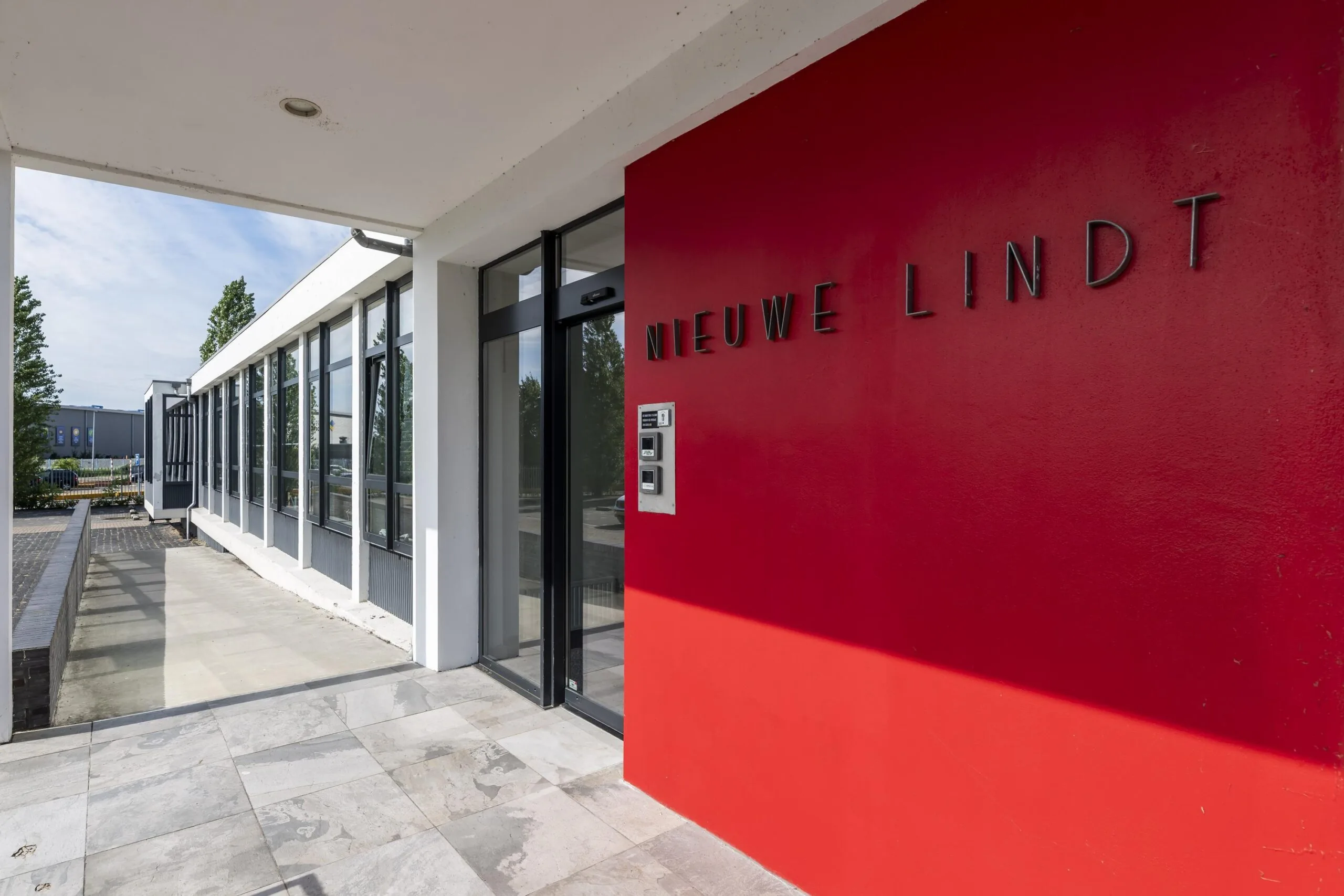 Ingang van het gebouw "Nieuwe Lindt" met een rode gevel en moderne glazen entree.