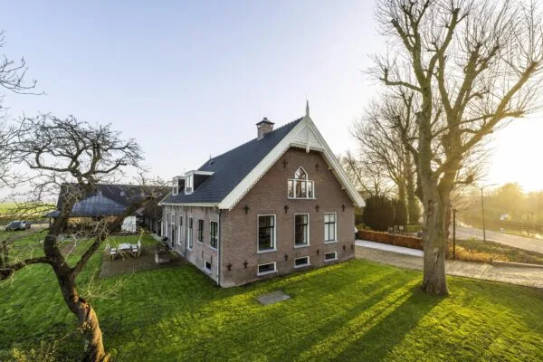 Woonboerderij aan de Gein-Zuid met ruime tuin en omliggend landschap in het ochtendlicht.