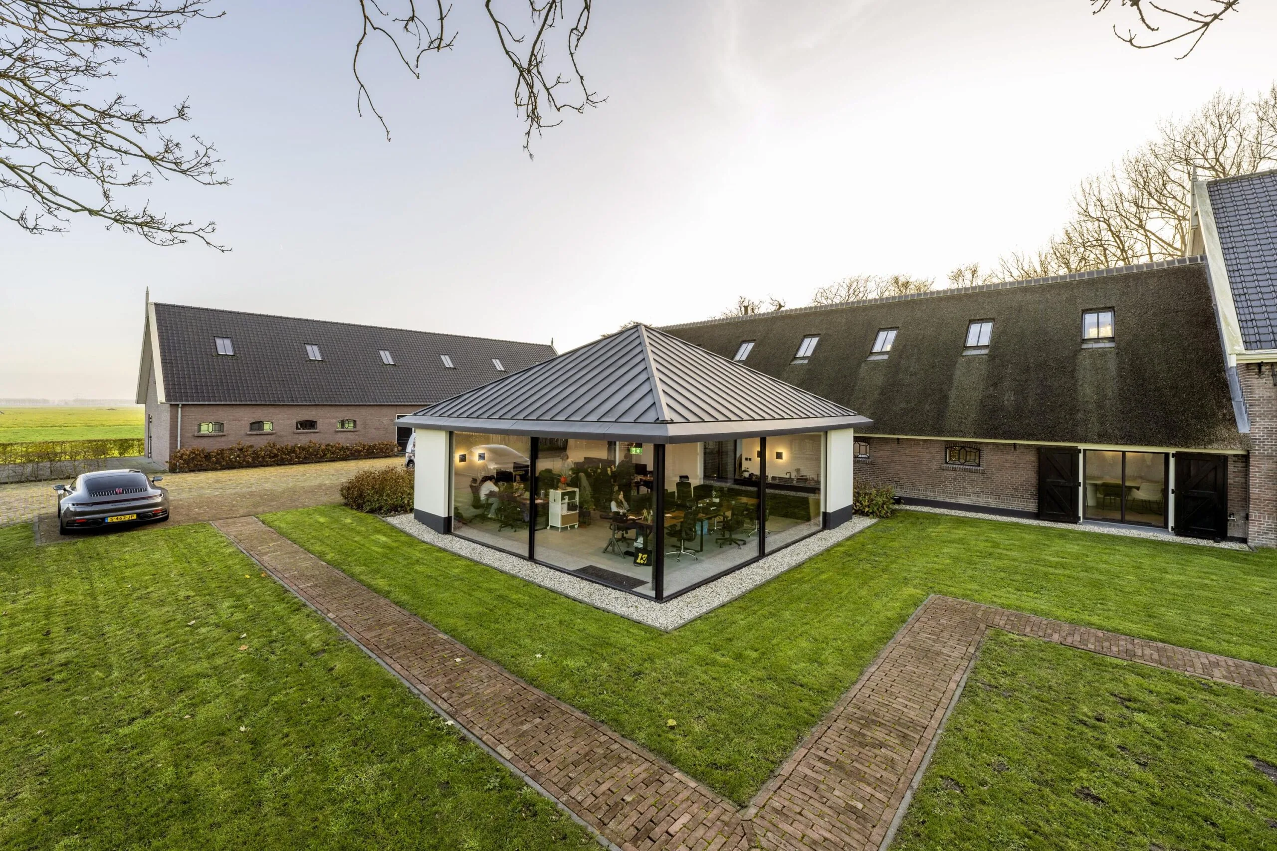 Moderne aanbouw met glazen wanden op binnenplaats van een traditioneel gerenoveerde boerderij aan Gein-Zuid.