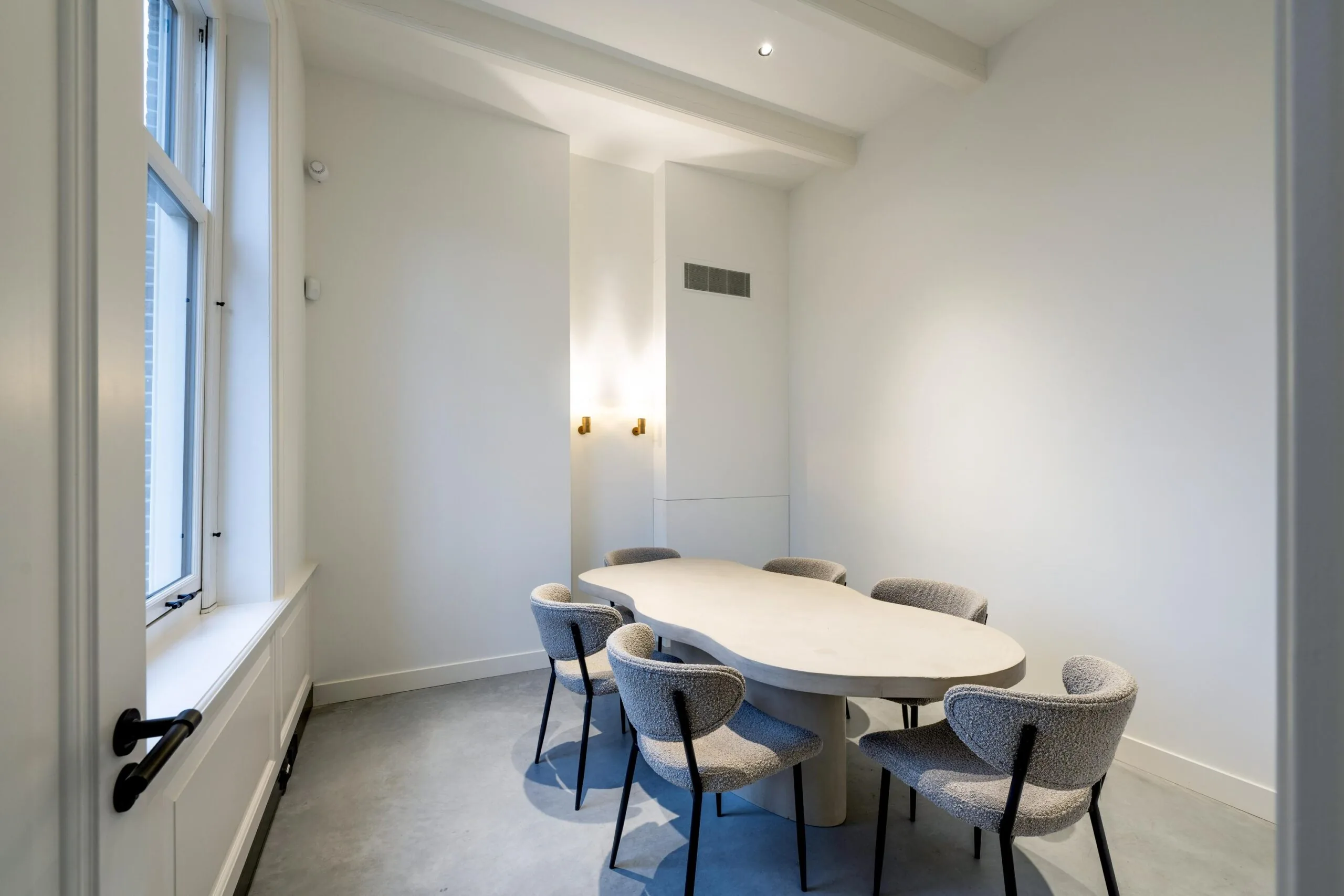 Minimalistische vergaderruimte in Gein-Zuid met een organisch gevormde tafel en zes gestoffeerde stoelen.