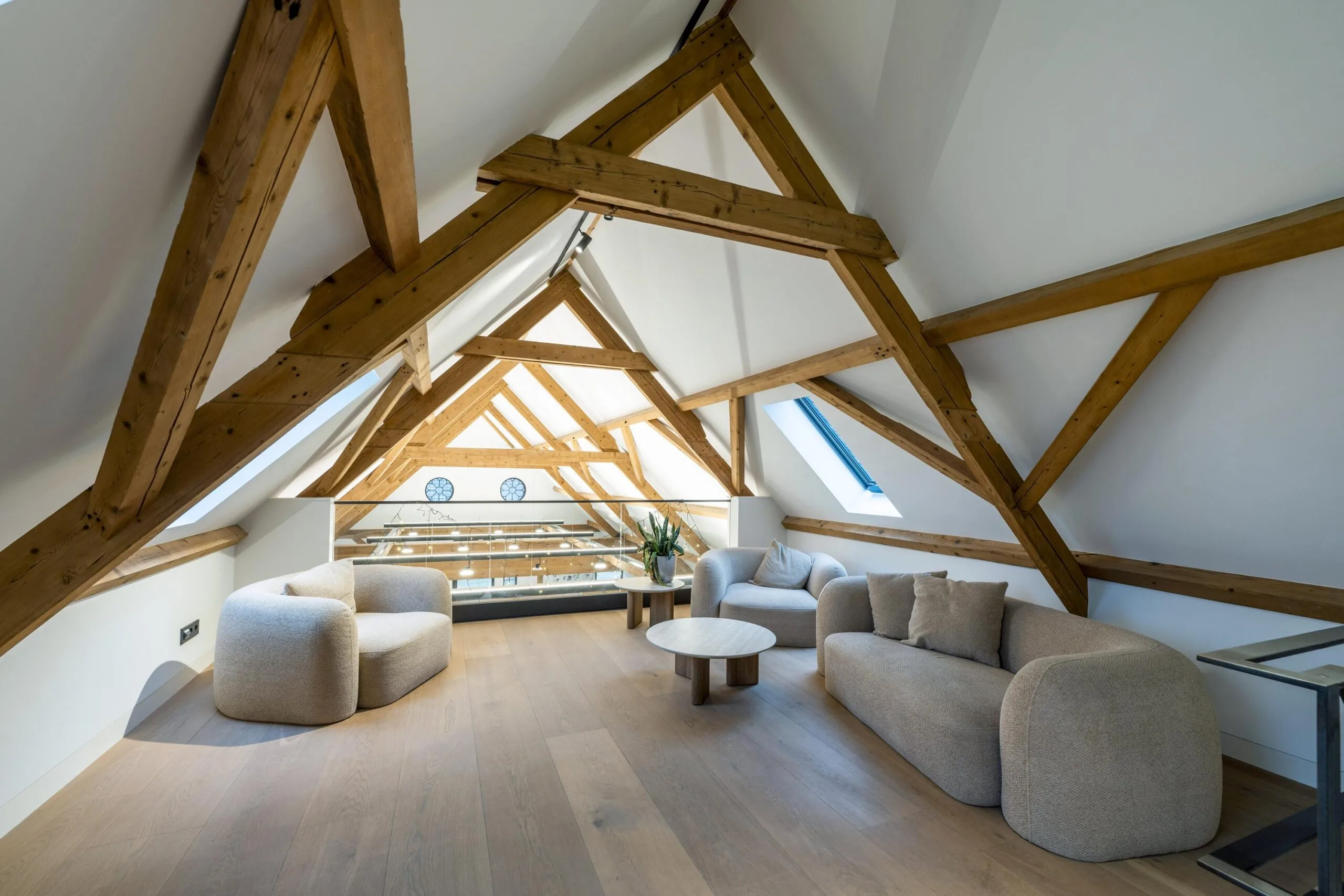 Modern ingerichte zolderruimte met zichtbare houten balken, zachte meubels en veel natuurlijk licht in Gein-Zuid.