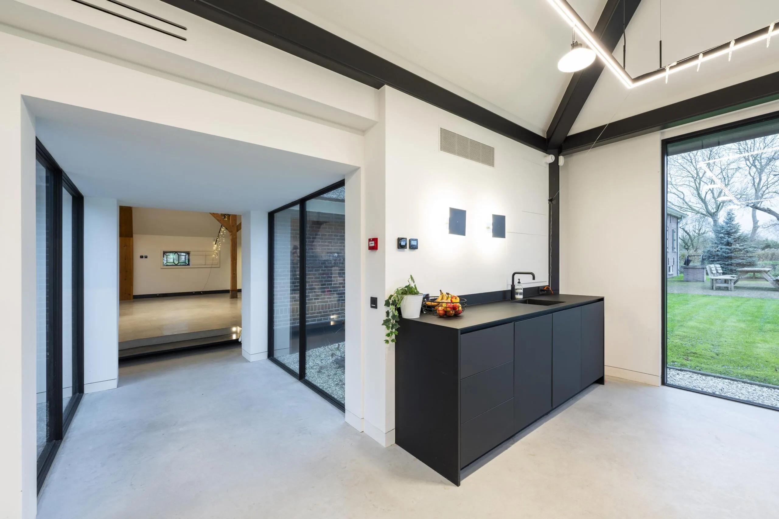 Moderne open keuken met zwart kookeiland en uitzicht op een groene tuin in een woning aan het Gein-Zuid.