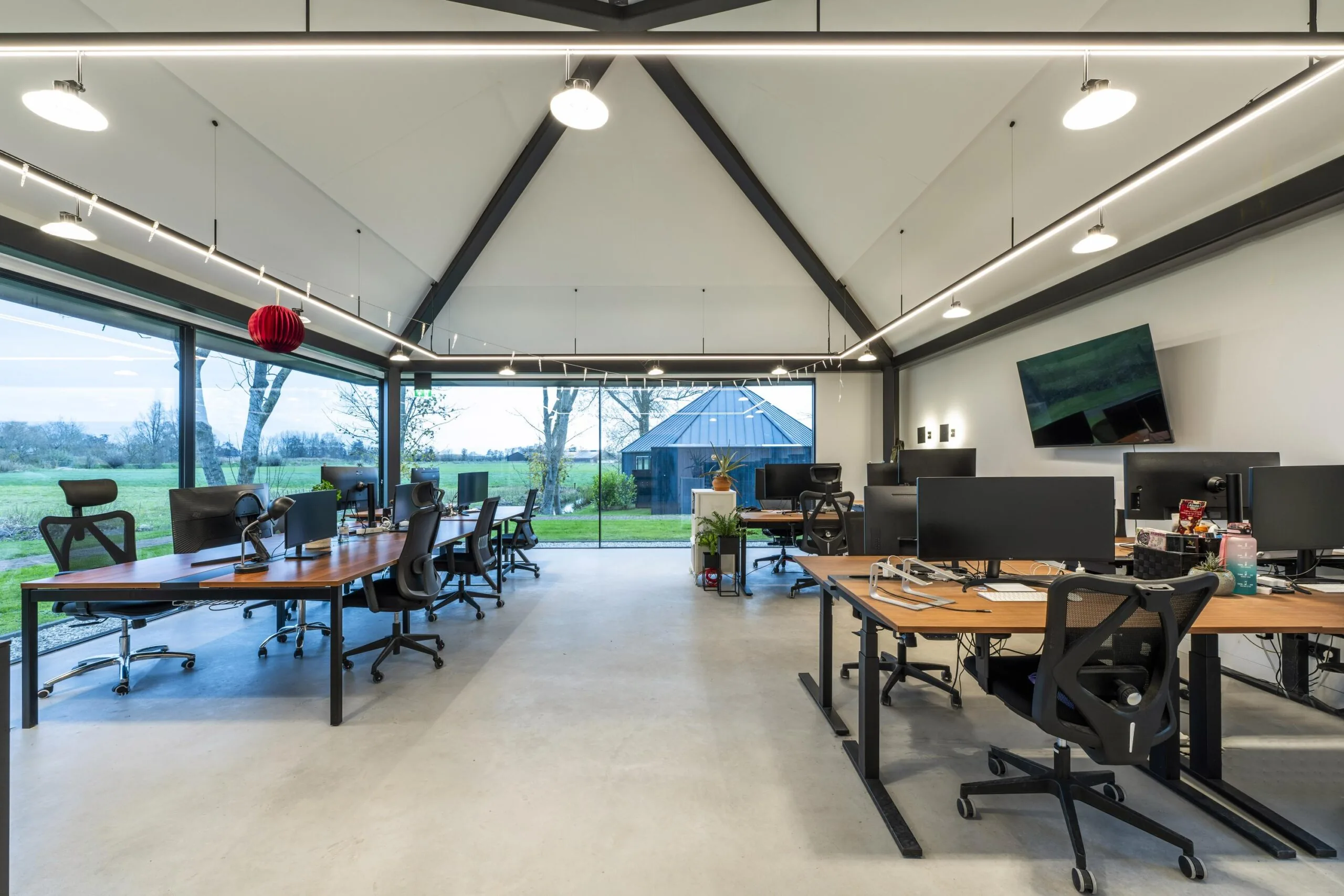 Moderne kantoorspace in Gein-Zuid met grote ramen, meerdere werkplekken en uitzicht op het groene buitenlandschap.