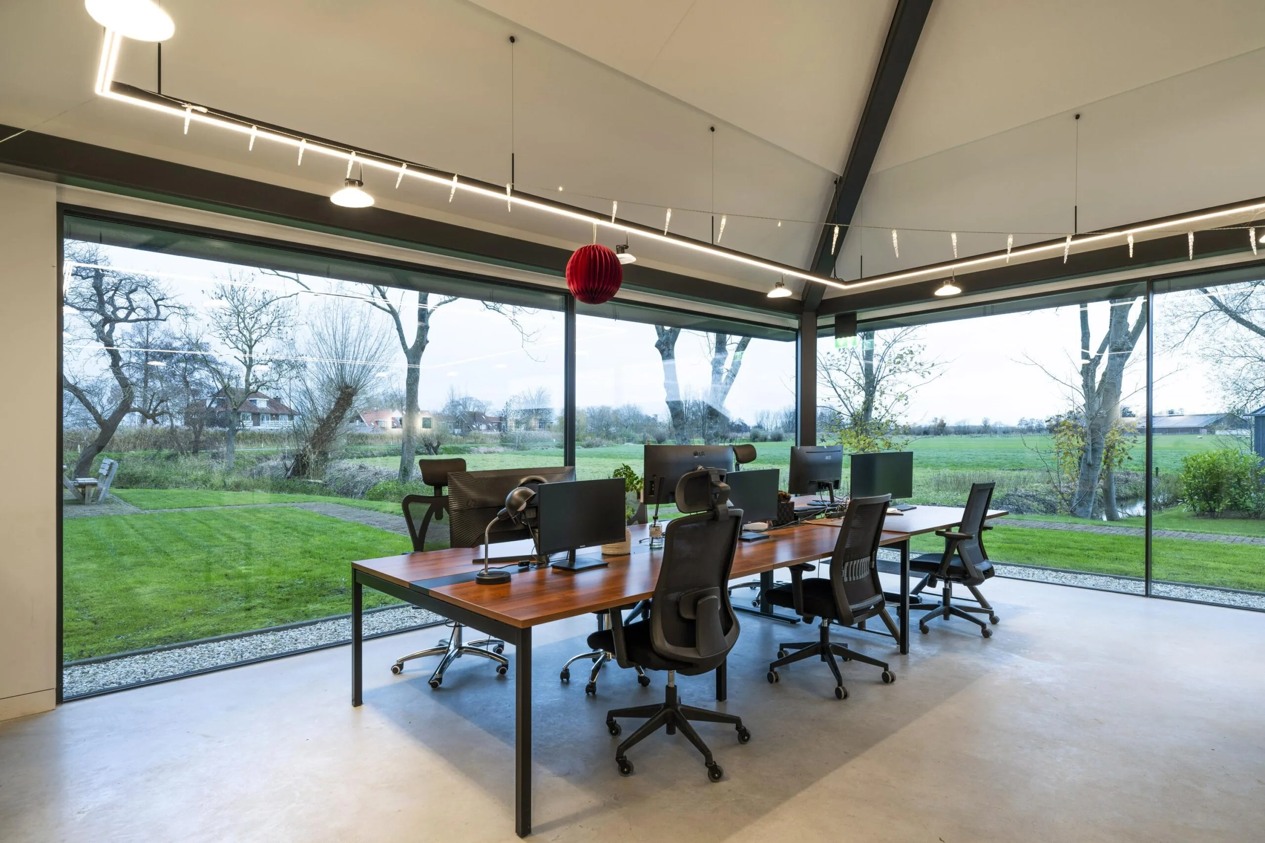 Modern kantoor met bureaus en computers in een glazen ruimte met uitzicht op het landelijke landschap van Gein-Zuid.