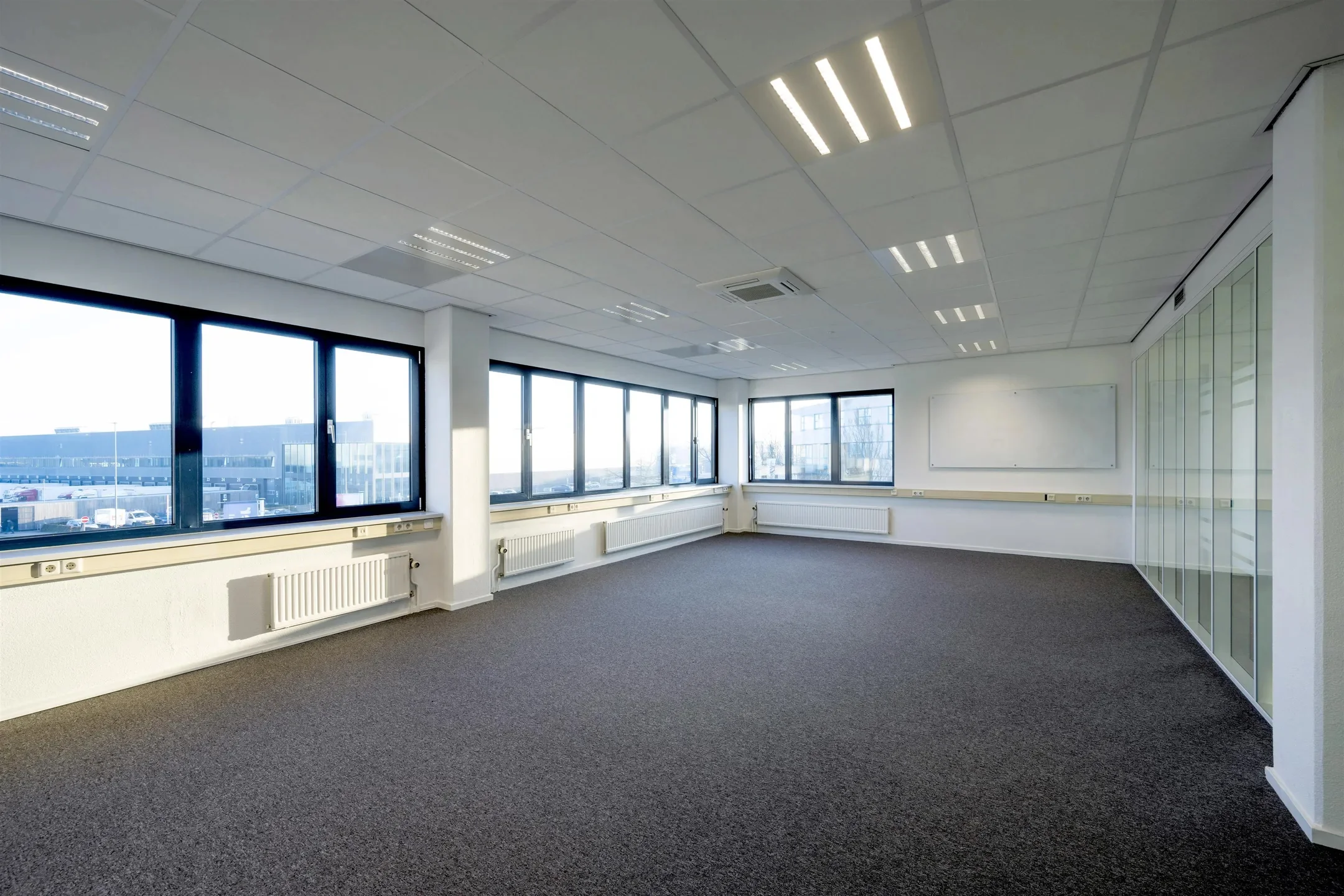 Licht en ruim leeg kantoor op de Kobaltweg met grote ramen en glazen wand.