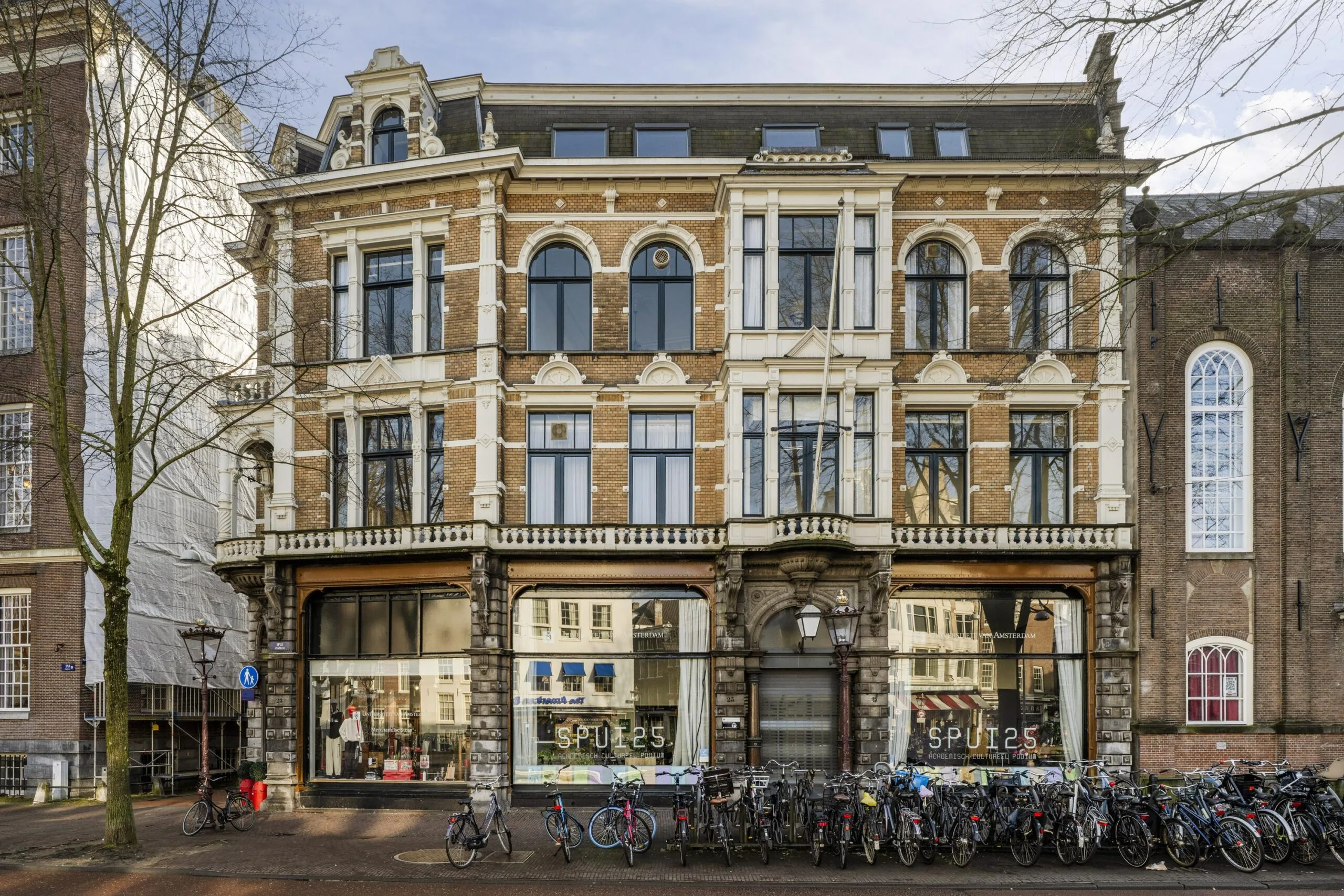 Een historisch pand met de naam Spui25 in Amsterdam, omgeven door fietsen.
