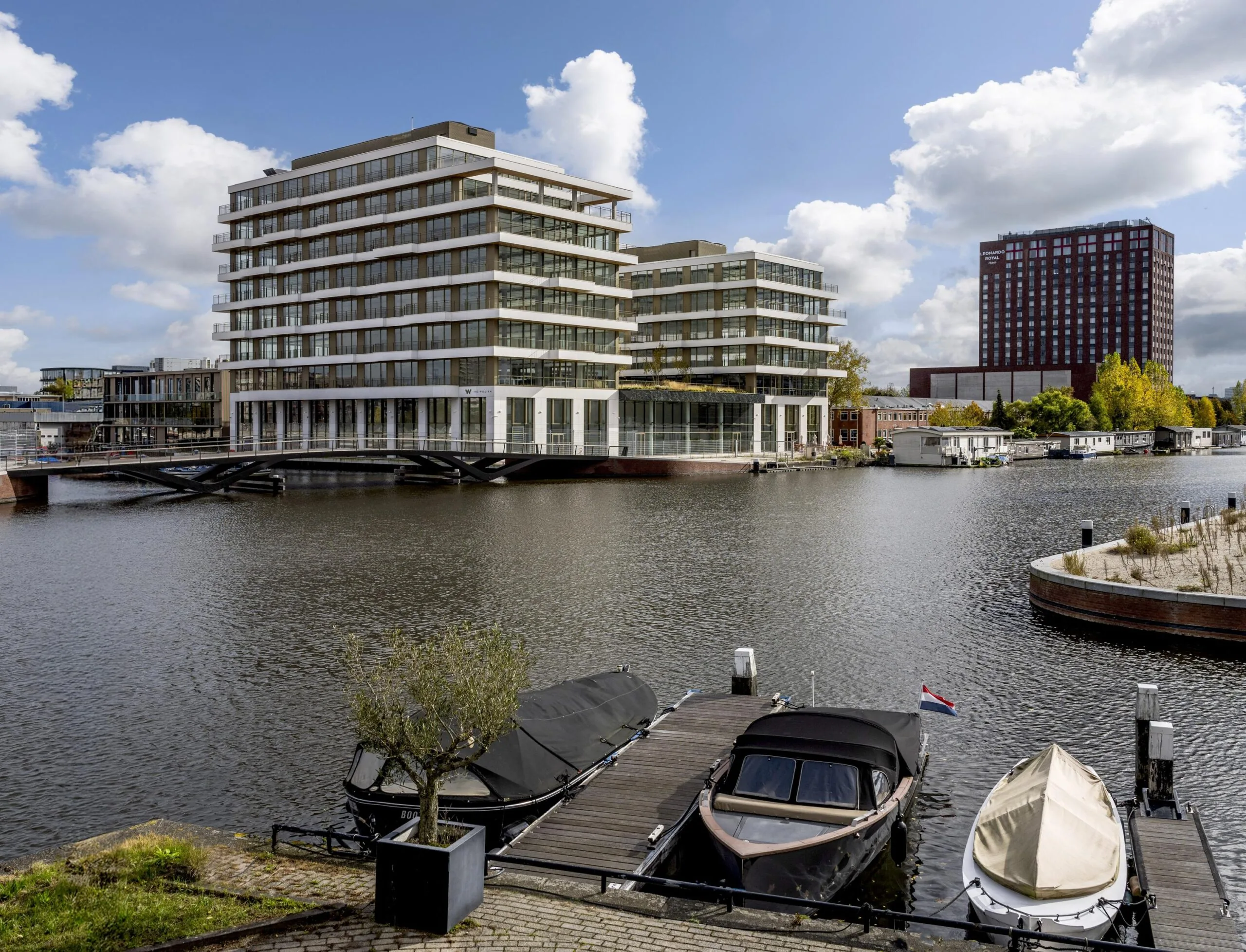 Een modern gebouw aan het water met aangemeerde boten aan de Willem Fenengastraat.