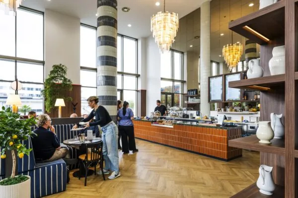 Een moderne koffiebar met houten interieur en grote ramen waar klanten worden bediend.