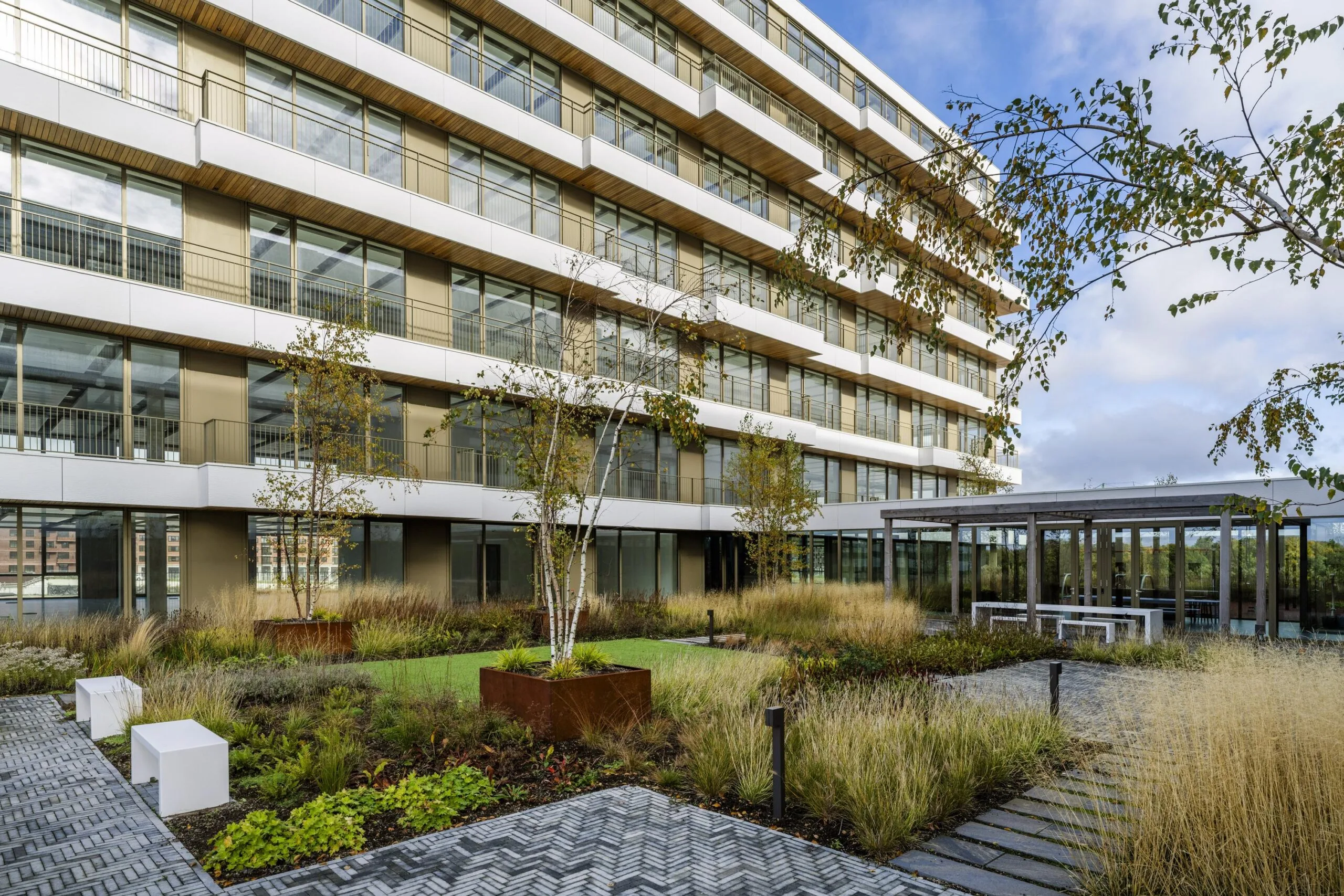 Een moderne gebouw met glazen gevel en een groene binnentuin aan de Willem Fenengastraat.