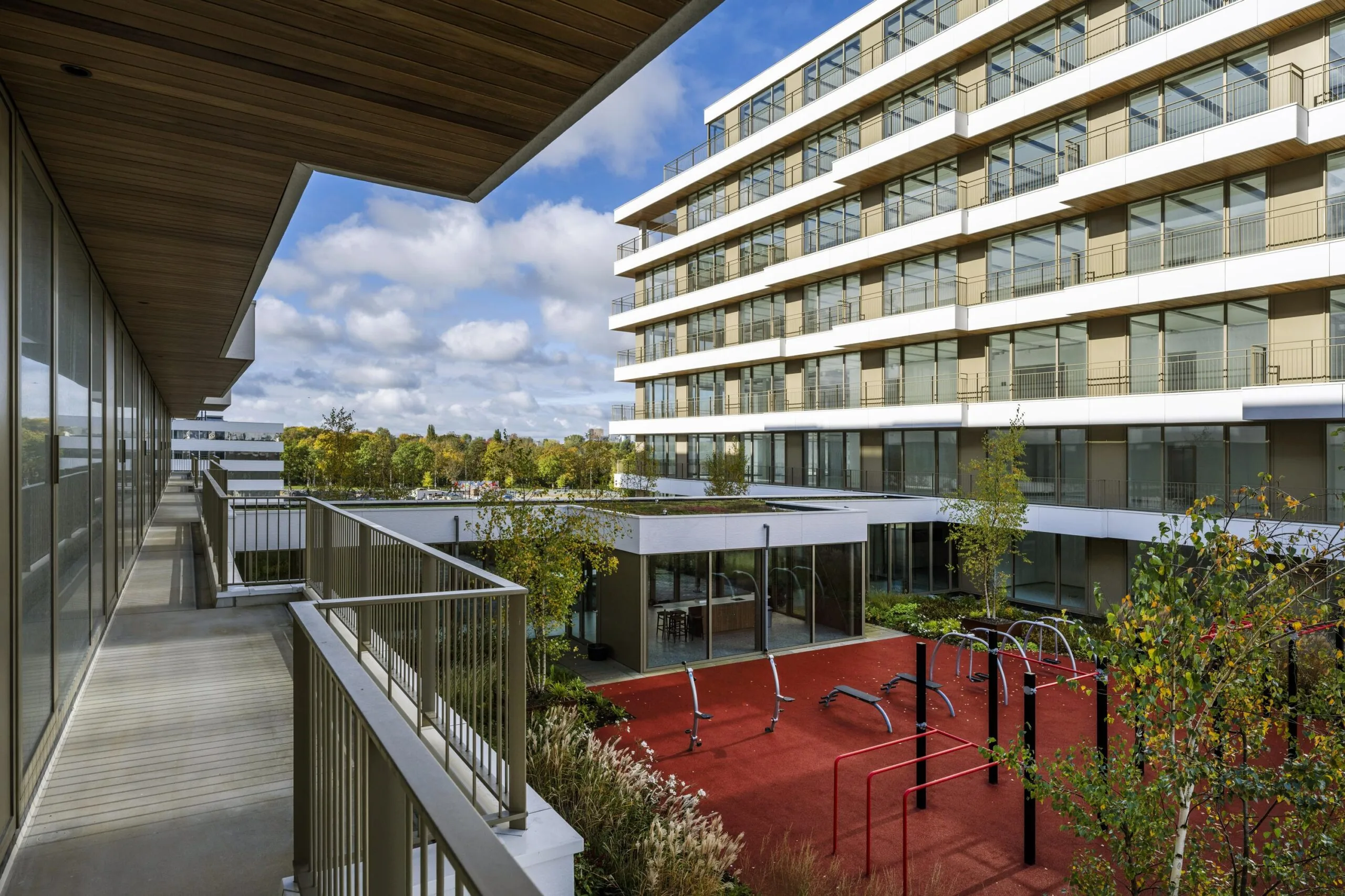 Appartementencomplex met een moderne gevel en een buitenruimte met fitnessapparatuur.