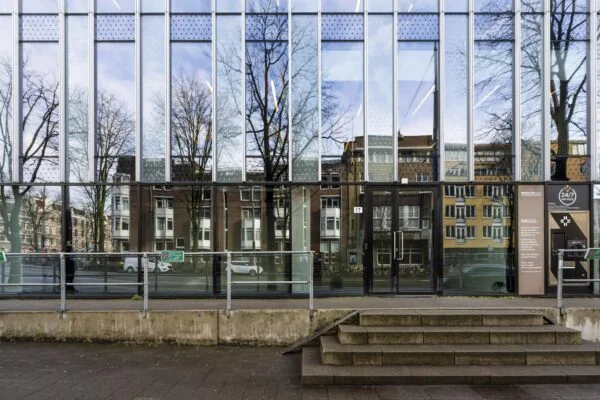 Een modern gebouw aan de Roetersstraat met glasgevels die de omgeving weerspiegelen.