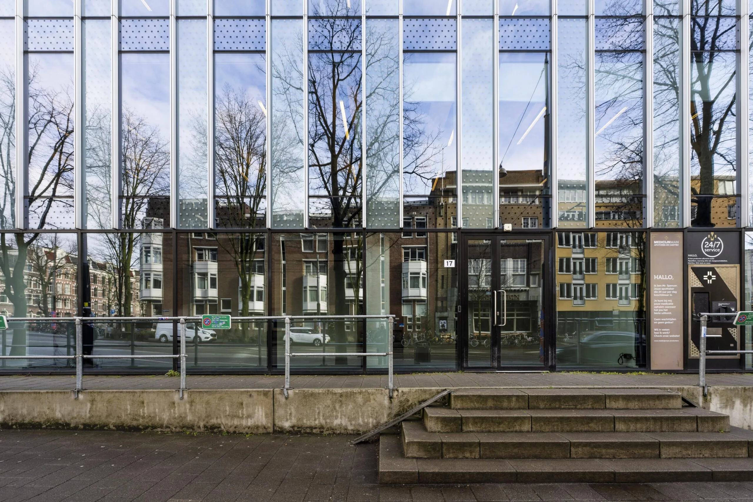 Een modern gebouw aan de Roetersstraat met glasgevels die de omgeving weerspiegelen.