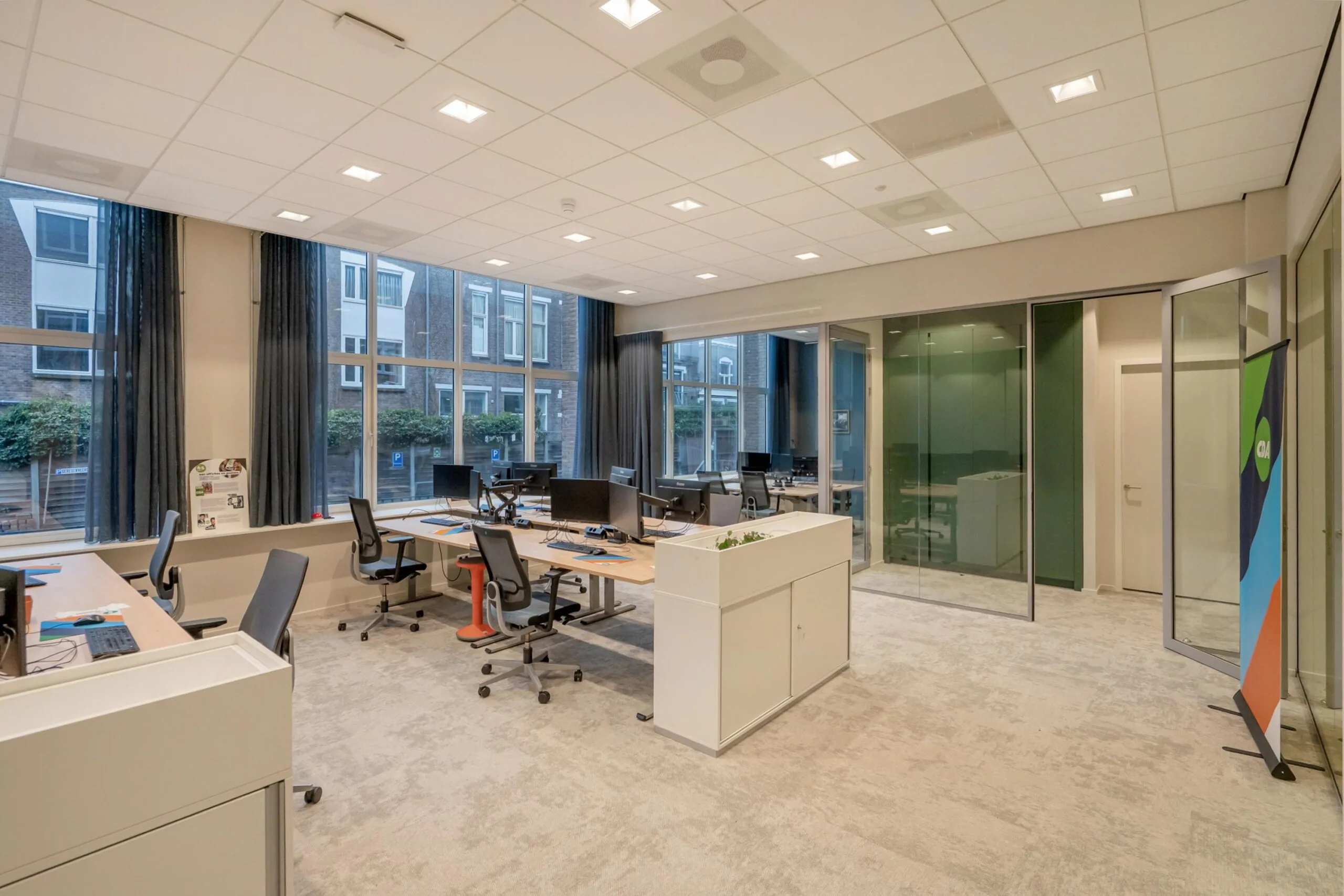 Een modern kantoor met meerdere bureaus en glazen wanden.