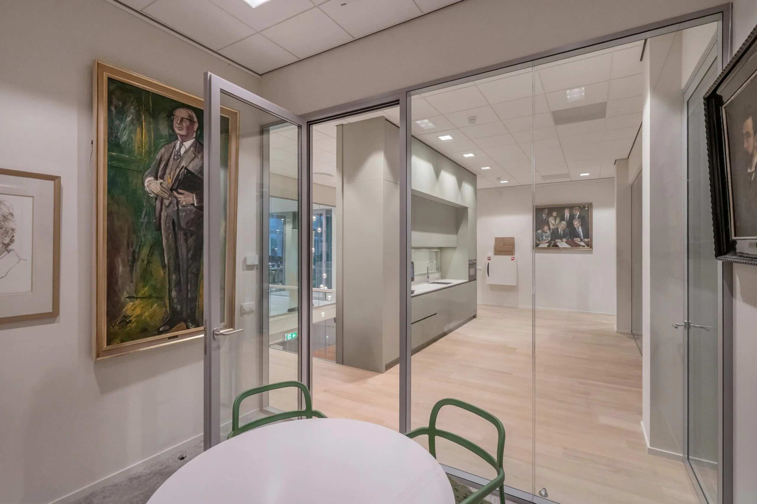 Moderne kantoorruimte met glazen wanden, kunstwerken aan de muur en een openslaande deur.
