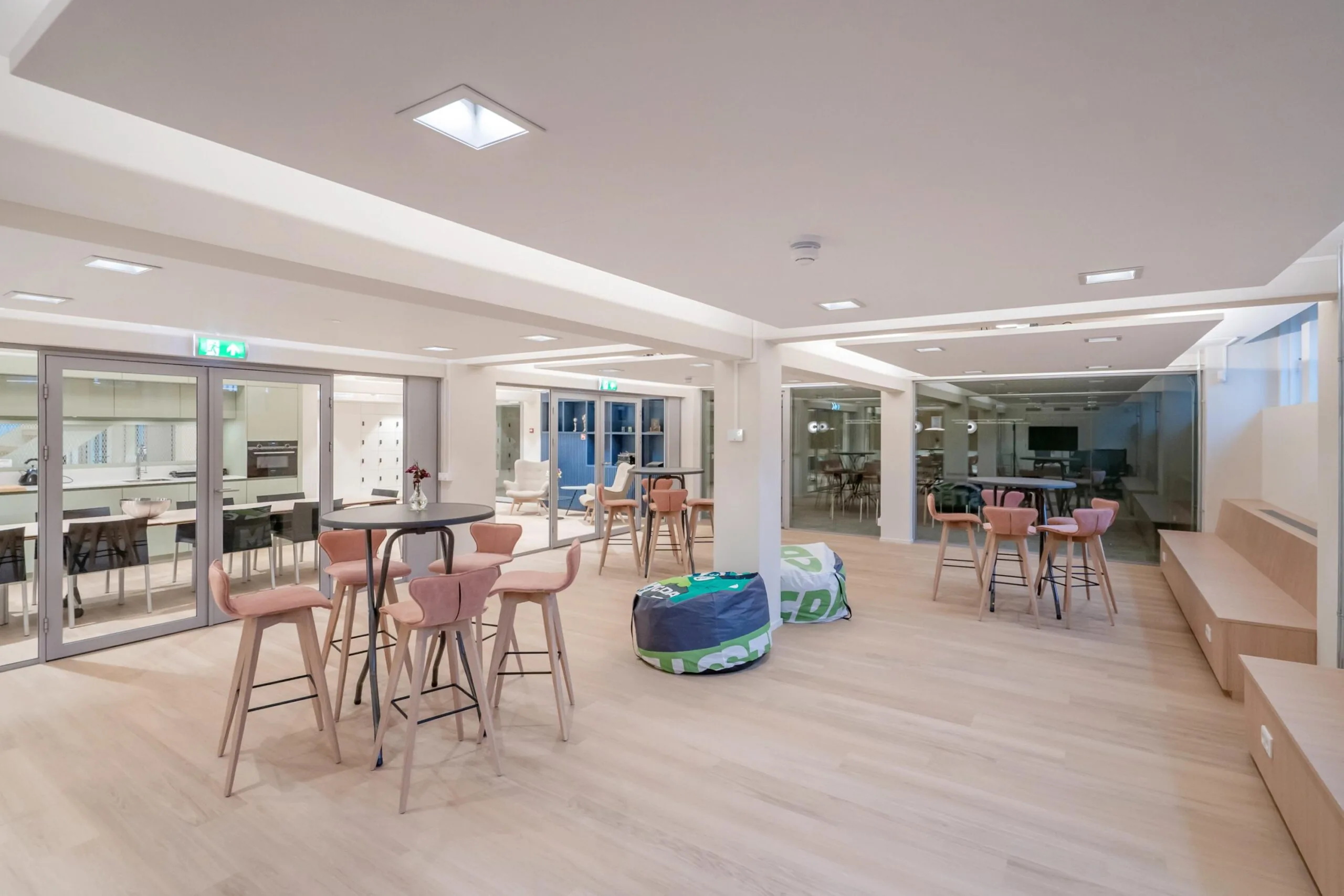 Een moderne, lichte gemeenschappelijke ruimte met tafels, stoelen en zitzakken.