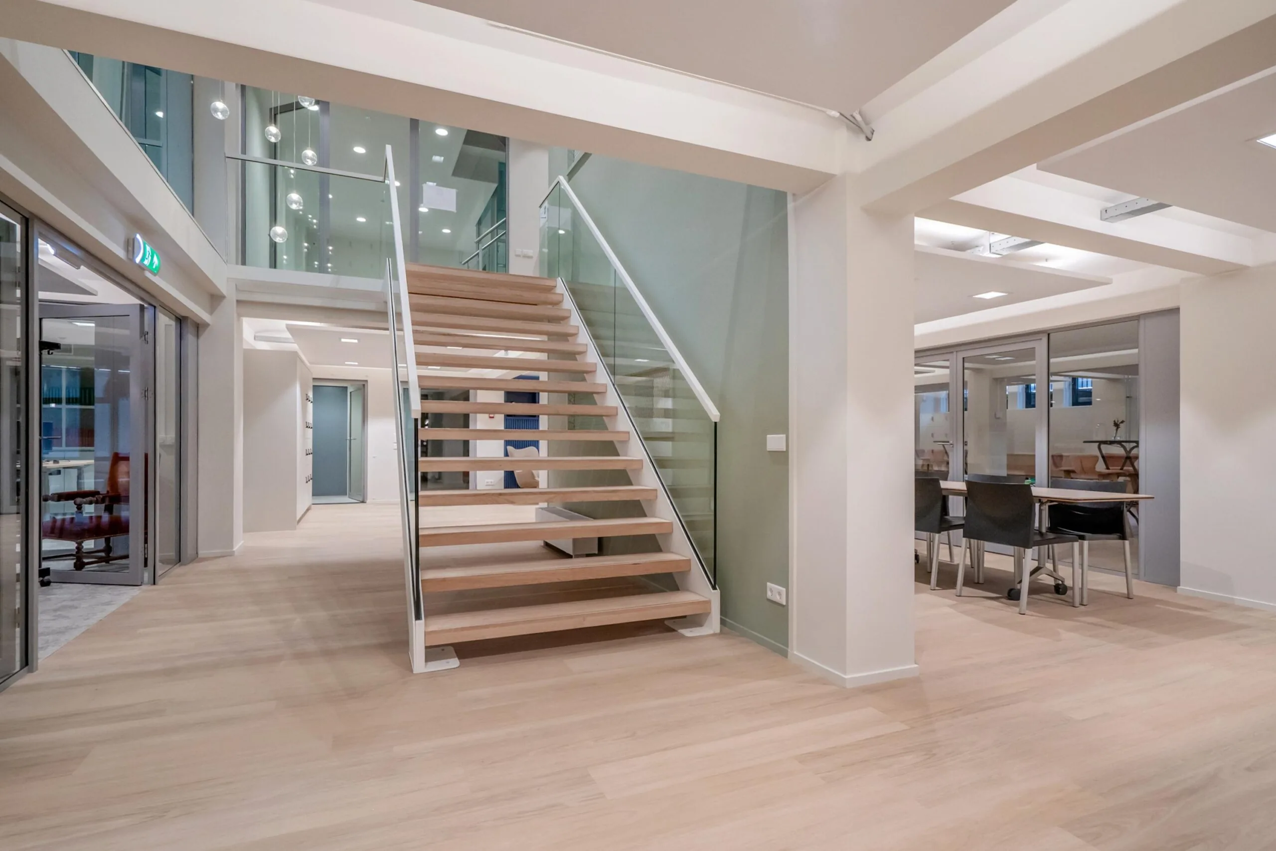 Een moderne open ruimte met een houten trap en glazen balustrades in een kantooromgeving.