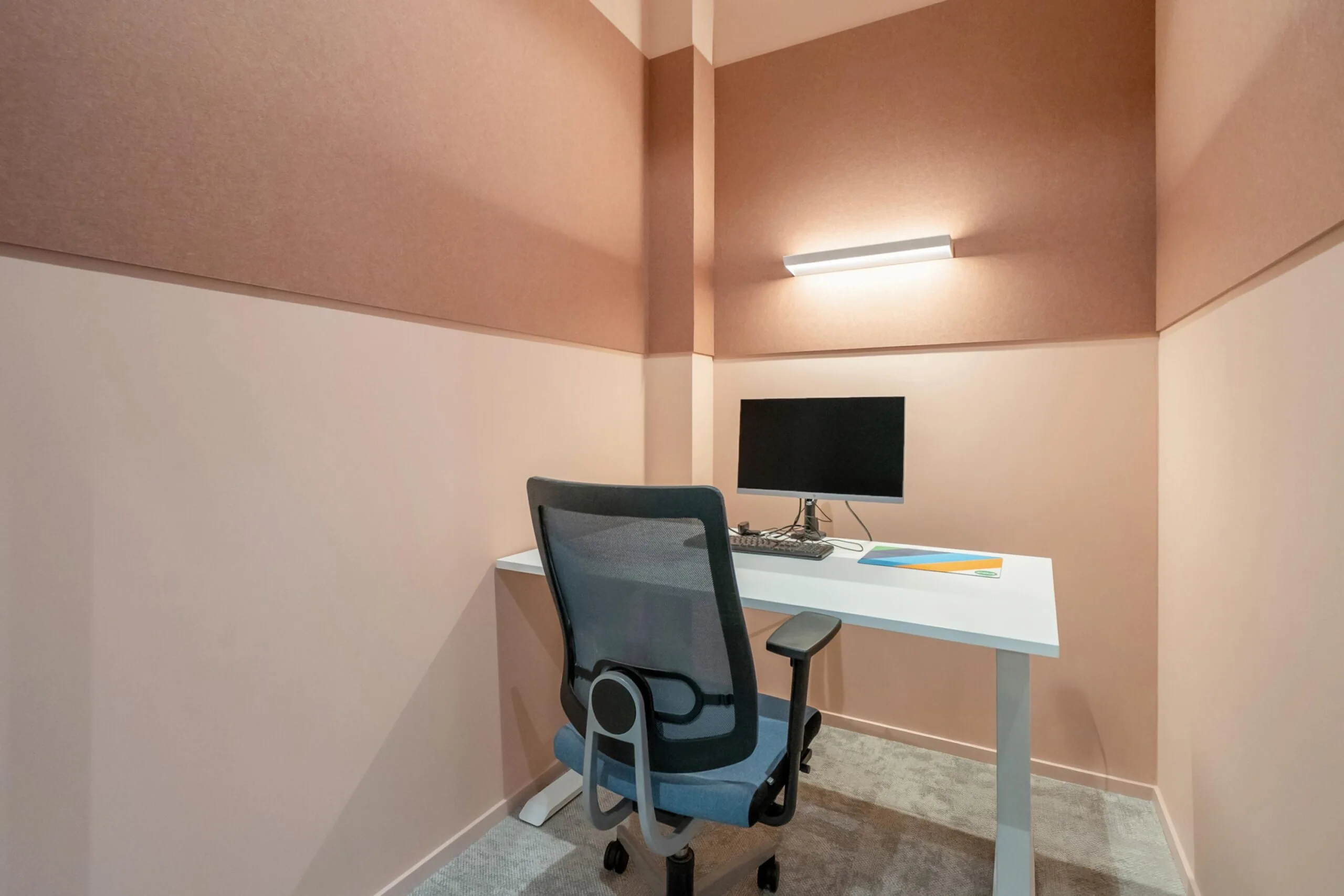 Een moderne, compacte kantoorruimte met een bureau, monitor en bureaustoel.