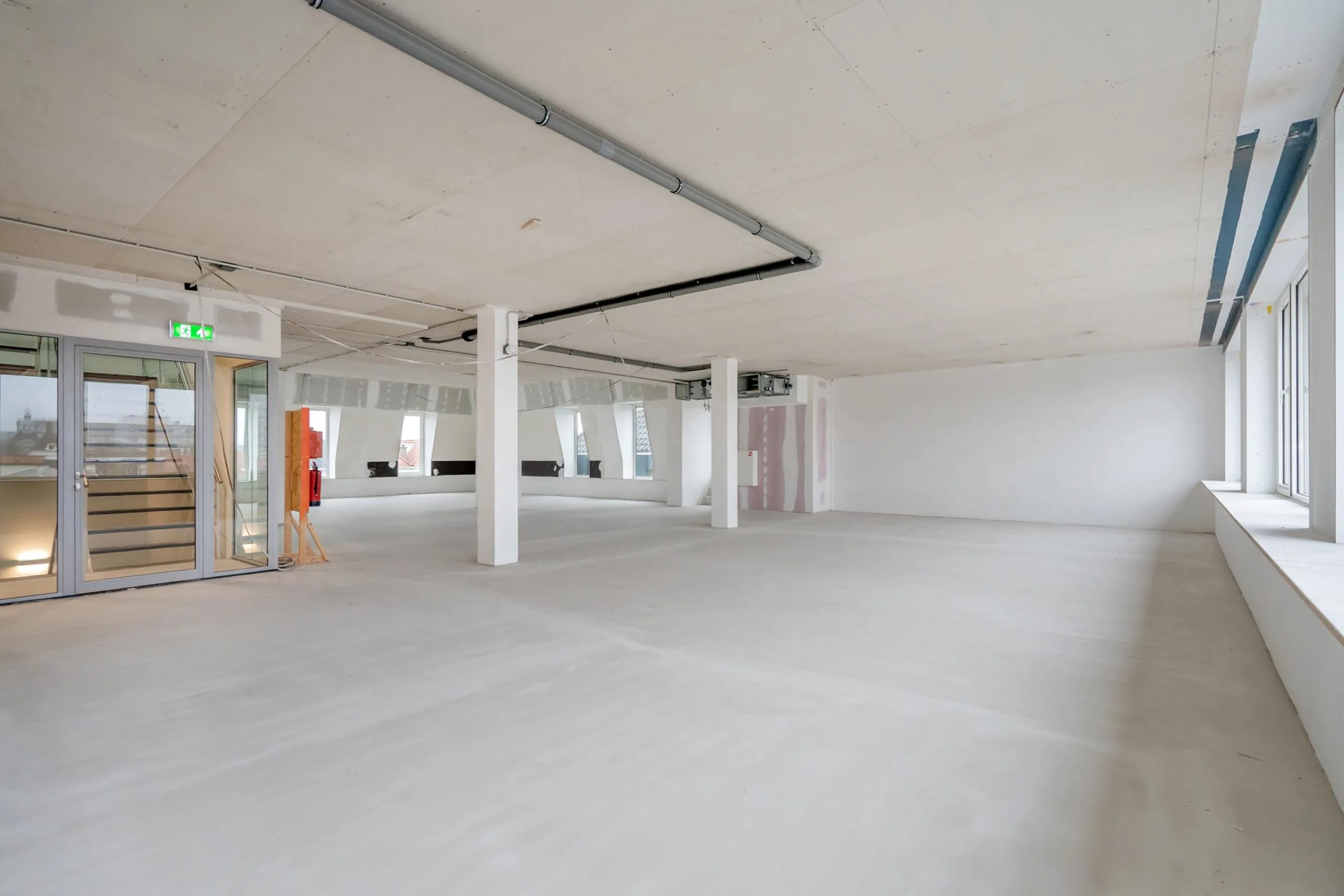 Lege industriële ruimte met grote ramen en betonnen vloeren.