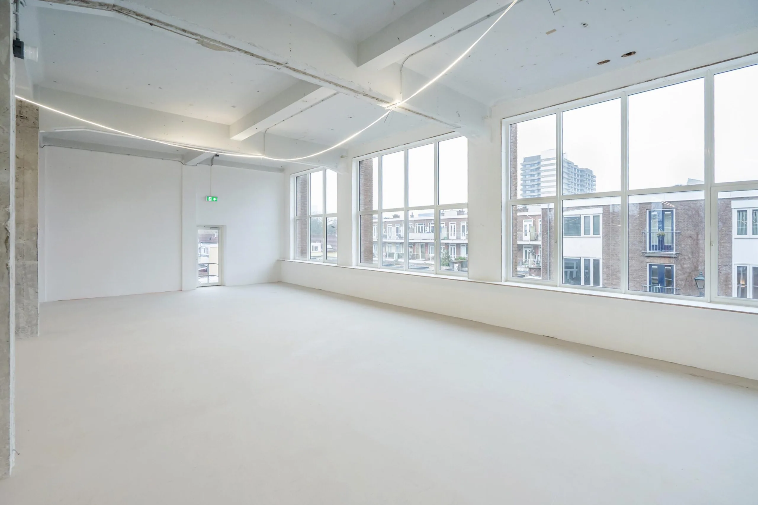 Licht, leeg kantoor met grote ramen en uitzicht op nabijgelegen gebouwen.
