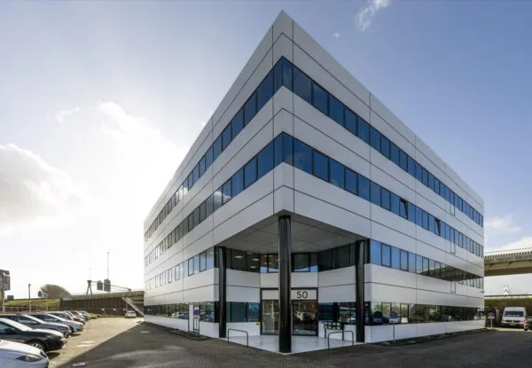 Een modern kantoorgebouw met grote ramen aan de Kuiperbergweg, onder een heldere lucht.