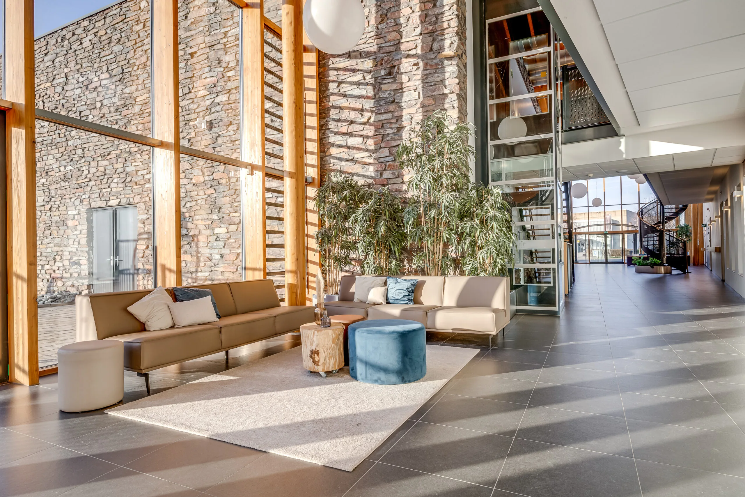 Een moderne, lichte lobby met een zithoek en grote glazen ramen.