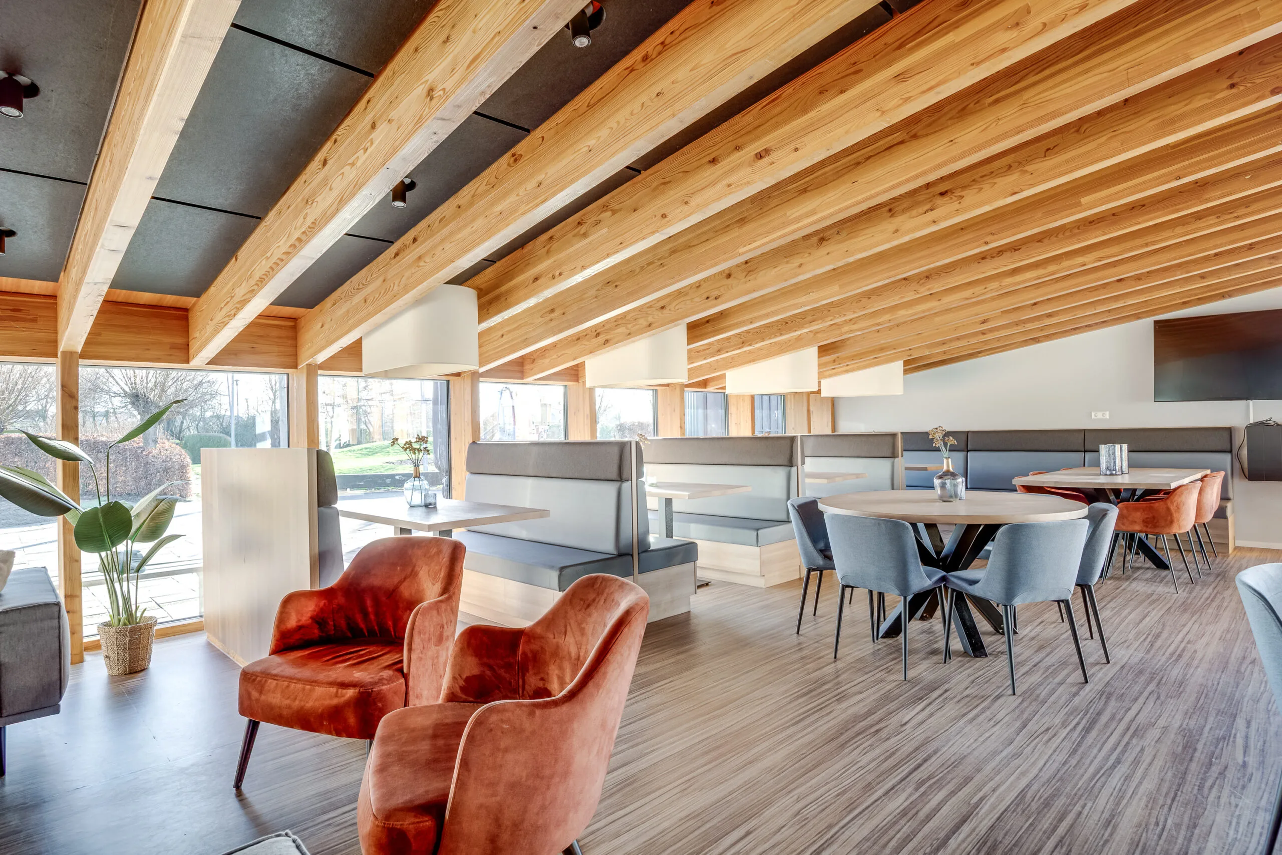 Een modern ingerichte ruimte met houten balken aan het plafond en comfortabele zitmeubels.