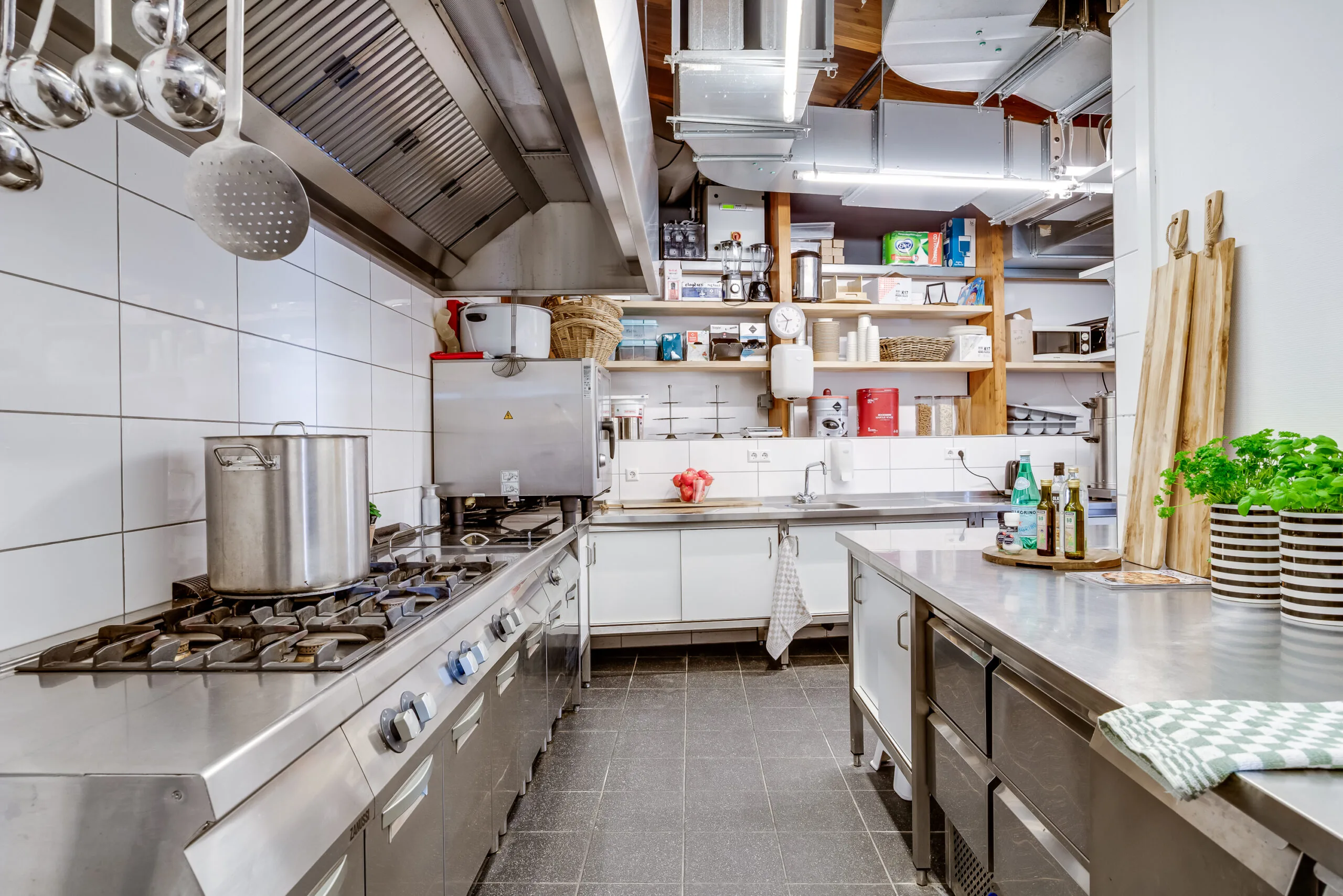 Een professionele keuken met roestvrijstalen apparatuur en kookgerei.