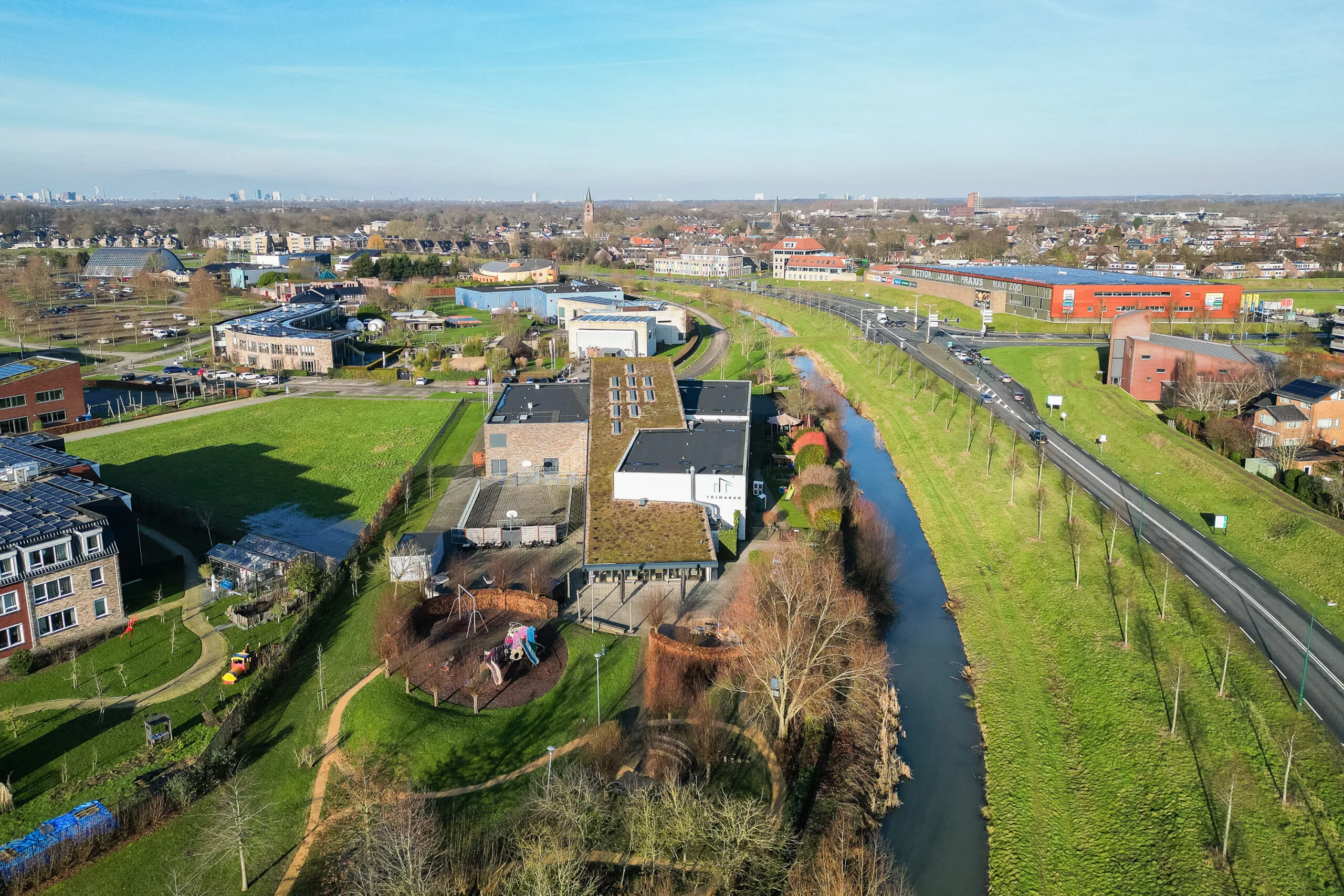 Luchtfoto van een groene buurt met een kanaal, wegen en verschillende gebouwen.