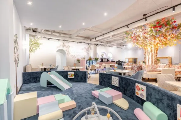 Speelruimte in een modern café met kleurrijke zachte speelobjecten en tafels met stoelen.