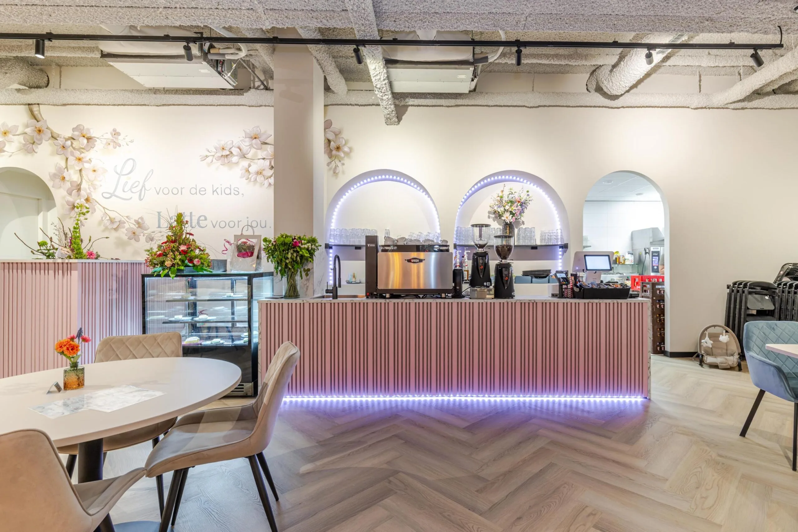 Een stijlvol ingerichte hippe koffiebar met een roze toon en gezellige bloemenaccenten.