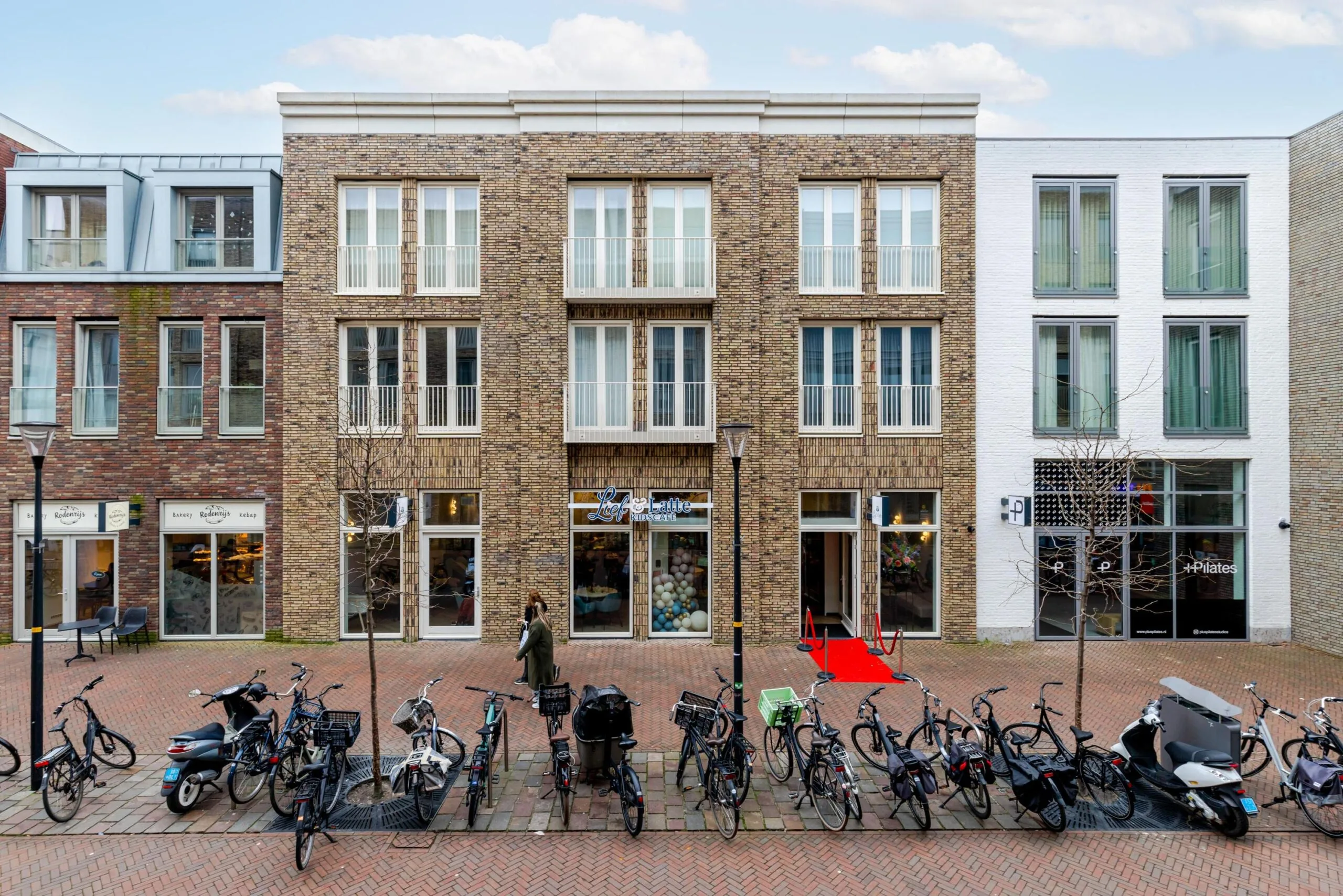 Een straatbeeld met een modern stenen gebouw aan de Westersingel, omgeven door geparkeerde fietsen en een voorbijganger.