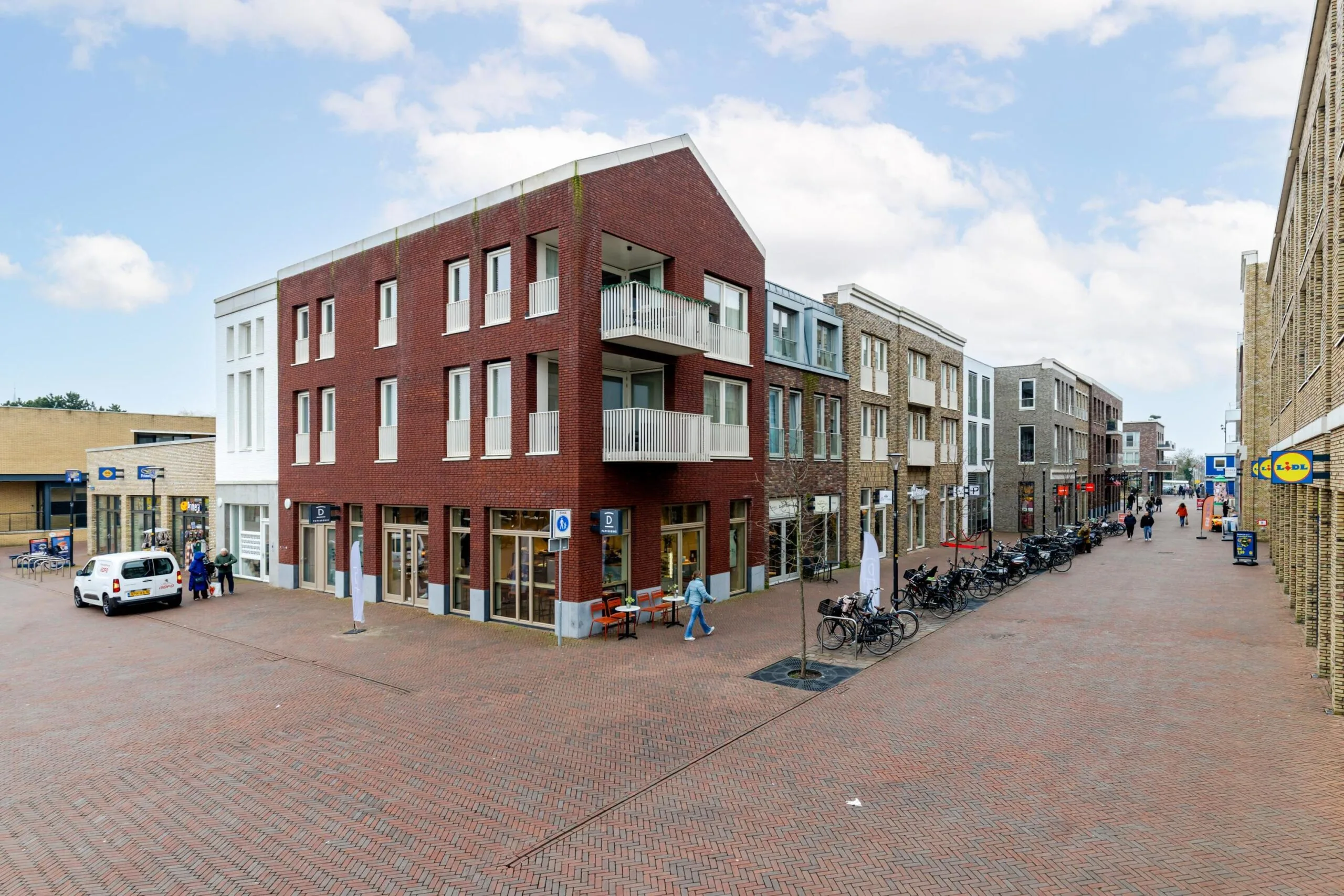 Straatbeeld van de Westersingel met moderne bakstenen gebouwen en winkels.