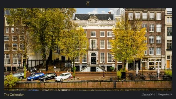 Gevel van een historisch grachtenpand aan de Herengracht, met gekleurde bomen en geparkeerde auto's langs het water.