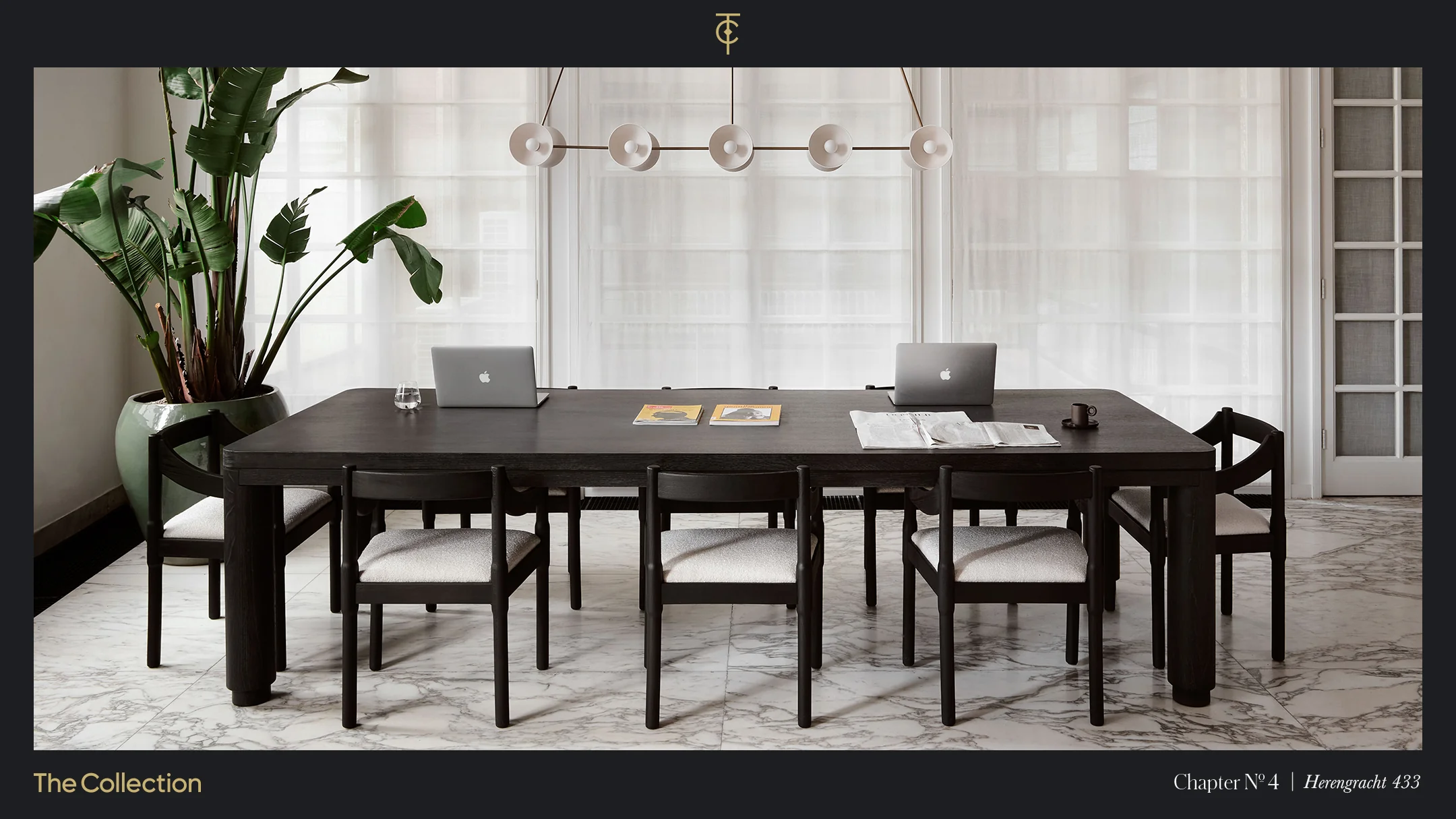 Een moderne vergaderruimte met een grote houten tafel, laptops, tijdschriften en een plant in een pot op de achtergrond.